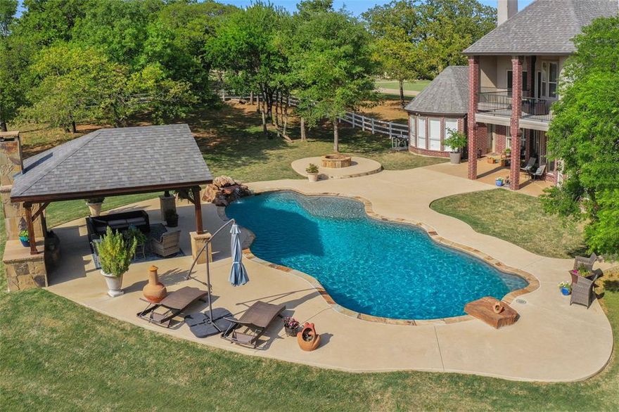 LOCATED IN ARGYLE ISD & NEAR LIBERTY CHRISTIAN! This luxury home is absolutely amazing and has all of the Argyle must-haves! The backyard oasis features a huge party pool with diving rock & waterfall, a covered outdoor living space with a wood burning fireplace, has a fire pit for cooler nights, and still has space for your horses! A small barn and cross fencing provide the perfect space.  The large covered outdoor patio is perfect for dining and is plumbed for gas. Inside, a second downstairs bedroom with an en suite bath and a private entrance suits guests or multi-generational living. Upstairs, the media room has a separate space for a game room or dining room and includes a wet bar. An added bonus: this home has a lightning protection system! 
This 2.5 acre property with mature trees is a rare find in Argyle! Schedule a tour today!