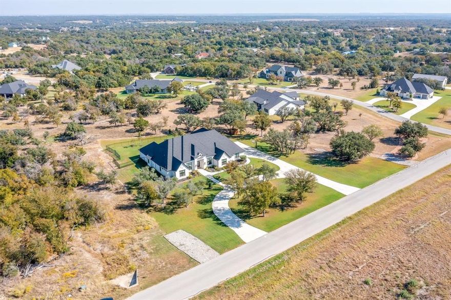 Couto Custom Home in Aledo is a stunning French Traditional Estate exuding timeless elegance & modern comfort. A grand U-shaped driveway sets the stage for this impressive executive home, offering a warm welcome to guests. Step inside to discover exquisite craftsmanship throughout, from extensive millwork & rich wood flooring to designer lighting, high-end fixtures, & architectural details that define sophistication. Set on 2 lush acres surrounded by mature trees & impeccable landscaping, this property offers privacy, serenity, & an inviting atmosphere. The chef’s kitchen is a true showpiece, featuring double islands, built-in appliances, a butler’s pantry, & walk in pantry, seamlessly connecting to the spacious dining area, ideal for hosting gatherings. The primary suite is a luxurious retreat with a stunning multiple tray ceiling, spa-like ensuite bath with dual vanities, a large walk-in shower with dual shower heads, & an expansive custom closet. Each of the four bedrooms offers generous space & comfort. Enjoy the dedicated study with French doors, a large game room with wet bar, & a state-of-the-art media room featuring a cove ceiling with LED lighting, surround sound, projector, screen, & tiered theater seating. The family room showcases a dramatic floor-to-ceiling stone fireplace & coffered ceiling, with double sliding doors opening to a private backyard oasis, the perfect space for entertaining or unwinding. Additional highlights include a whole-home generator; Michael Phelps swim spa; & an attic lift providing easy access to a fully insulated storage space above the garage. This extraordinary home is more than a residence — it’s a personal retreat where luxury, comfort, & thoughtful design come together. Relax in your private spa setting or entertain with confidence, knowing every detail has been crafted to impress. ONLY 9.5 MILES TO LOCKHEED MARTIN. HIGHLY SOUGHT AFTER ALEDO ISD.