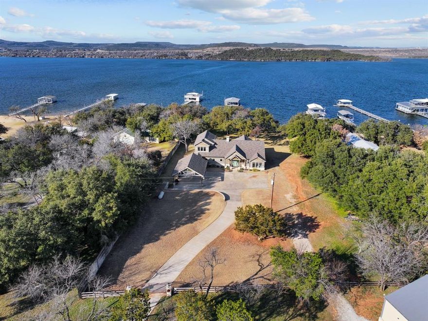 Welcome to an exquisite lakeside retreat, accessible through gated entry, where tranquility and luxury seamlessly blend into nature's splendor. Nestled on over two acres of pristine waterfront, this sanctuary is adorned with majestic oaks, offering a serene escape from the hustle and bustle. The custom-built home boasts five bedrooms and four baths, including a spacious bunk room perfect for guests. The heart of the home is a designer kitchen, featuring a sprawling island and top-of-the-line appliances. The main level hosts the primary suite, a retreat in itself with an ensuite bath and dual vanities. The living room exudes warmth with beamed wood-vaulted ceilings, adjacent to a cozy screened porch. Kids and pets will delight in the lush play yard, leading effortlessly to the sandy beach lakefront. Enjoy amenities like a carport, a 2400-square-foot boat barn for all of your lake toys, and an oversized dock with lifts. Relax on the covered lakeside patio or the open fenced area, perfect for gatherings. This property is both 1931 Deer Trail Rd and includes 1929 Fawn Circle therefore price per square foot is not accurate. 1931 deer Trail offers the home finished in 20 Dock new as of 21. 1929. Fawn is nearly an acre, dockable and houses the 2400 square-foot boat barn combined equals 2+ acres.