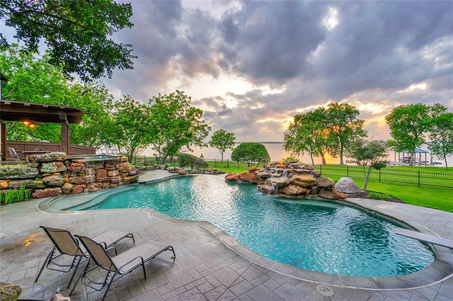 MULTIPLE OFFERS RECEIVED.This California-inspired prime lakefront custom residence on .79 acres offers a dynamic blend of luxury craftsmanship and exceptional outdoor living. Designed to capture sweeping sunset views of Lake Ray Hubbard, the open-concept floor plan showcases walls of windows, creating a constant connection to the water. True quality is found not only in what you see, but in how the home was built. Constructed with 2x6 framing, Tyvek wrap, radiant barrier, solar attic fans, and a tankless water heater, this home was designed with enduring craftsmanship and energy efficiency in mind. Timeless finishes and natural materials blend with a crisp white aesthetic & modern lighting. Dual staircases, 4 fireplaces, wood floors and a circular driveway add warmth and architectural presence. The main level is thoughtfully designed with curated spaces, including a study, spacious family room with fireplace, luxurious Primary Suite, and an additional bedroom. The kitchen features double ovens and a commercial 6-burner gas cooktop. The large Primary Suite offers a fireplace and direct outdoor access. Upstairs, a large secondary living area with wet bar and fireplace is complemented by 3 bedrooms and a versatile bonus room ideal for a gym or media space. At day’s end, take in the sunset on the upper party deck. The outdoor experience is nothing short of a private resort. Multiple covered patios, an outdoor fireplace, and pergola lead to a resort-style elevated infinity-edge diving pool with a dramatic waterfall feature. Extending the estate to the shoreline, the private dock is equipped with a boat lift and jet ski lifts, offering immediate access to boating & paddleboarding. Car enthusiasts will appreciate the expansive 4 car garage featuring epoxy floors, workshop area, overhead rolling doors, generous storage and additional parking pad.No HOA. After a busy day, you’ll appreciate the sense of arrival as this luxury estate welcomes you to you own private sanctuary.