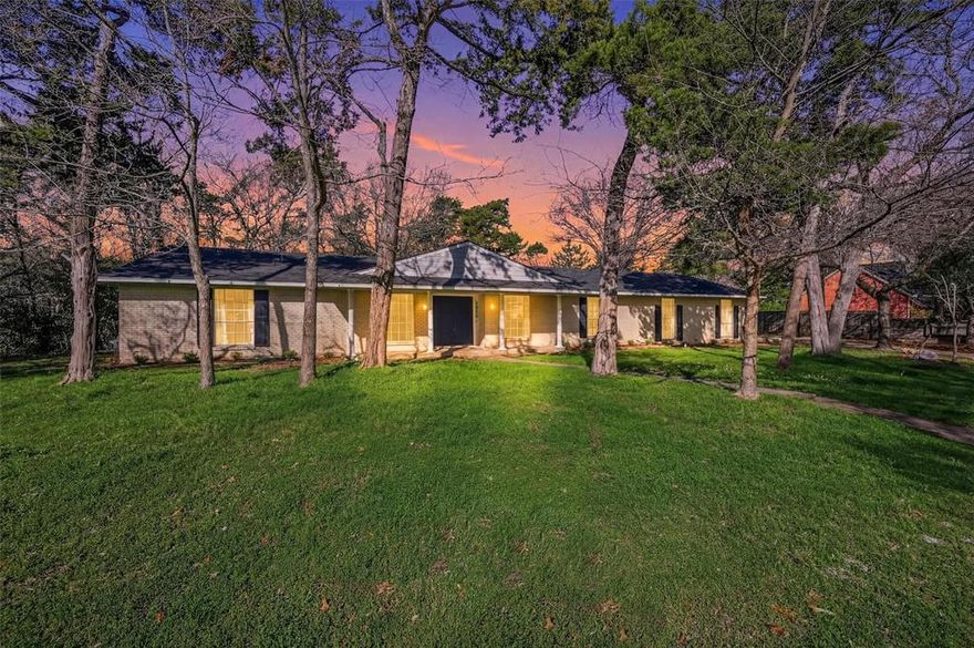 Welcome to your private retreat nestled on a beautifully treed lot--over one half acre--where timeless charm meets thoughtful updates and modern comfort. This spacious single-story home offers an inviting open-concept layout with rich wood flooring, exposed beams, and a stunning brick fireplace that anchors the main living area. The expansive living space flows seamlessly into the kitchen, featuring granite countertops, stainless steel appliances, abundant cabinetry, and a large breakfast bar—perfect for entertaining or everyday living. The home offers generously sized bedrooms, including a spacious primary suite with an ensuite bath and walk-in closet, while additional bedrooms provide flexibility for family, guests, or a home office. Each space has been thoughtfully designed to highlight comfort, functionality, and a warm, inviting feel. The bathrooms have been tastefully updated with a blend of classic and modern finishes.  Multiple outdoor living spaces add to the appeal. A serene sunroom surrounded by nature and an expansive elevated deck is ideal for relaxing, entertaining, or enjoying peaceful views of the surrounding trees. The property has been expanded, with a separate garage, to allow the original garage to be converted into an additional living space with a bedroom, half bath, and large family room. In addition, a new roof with class 4 shingles was installed in 2020, and the two AC units were replaced in 2023 & 2024. The property sits on a large, private lot with mature trees, offering both beauty and privacy rarely found at this price point. Conveniently located with easy access to nearby amenities, while still providing a quiet, secluded feel, this home is a rare opportunity to own a tranquil retreat with modern updates and exceptional indoor-outdoor living.