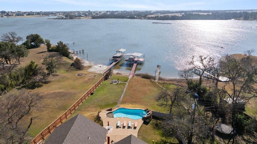 SHHHHHH....WELCOME TO WAXAHACHIE'S BEST KEPT SECRET...LAKE WAXAHACHIE!!! THIS IS THE PLACE TO MAKE FAMILY MEMORIES THAT LAST FOREVER!!! This RARE LAKEFRONT DEEP WATER PROPERTY offers PRIVATE LAKE ACCESS ON OVER AN ACRE, just minutes from historic downtown Waxahachie. The beautiful stone front, two story ENTERTAINER'S HOME features 4 bedrooms and 2 baths (option for 3rd full bath upstairs) with SOARING CEILINGS, ELEGANT WINDOWS, AND SKYLIGHTS THAT FRAME STUNNING LAKE VIEWS THROUGHOUT. EVERY BEDROOM HAS A UNBELIEVABLE LAKE VIEW. The luxurious primary suite is a true retreat with lake views, fireplace, his-and-her walk-in closets, and a spa-like ensuite boasting a jetted tub, walk in shower, dual vanities, skylight and hidden TV mirror. Enjoy a SOUNDPROOF BUILT-IN THEATER, a CHEF'S GOURMET KITCHEN with custom cabinetry, granite countertops, center island, GAS COOKTOP, and built-in oven and microwave overlooking the lake. Double doors lead out to the GORGEOUS view of the lake and tons of PATIO with an WATERFALL INGROUND  POOL to soak up every angle of the Lake. Enjoy year round fun in the pool WITH A TANNING LEDGE & a BAR TOP perfect for bar stools on the pool lake side. Take a stroll down the stone path that leads to the lake and stop by a cozy FIRE PIT for relaxing with family and friends any time of the year. A PRIVATE COVERED DOCK WITH A BOAT LIFT AND JET SKI STORAGE, perfect for fishing or sunset views. WELCOME HOME LAKE LOVERS, where everyday feels like a vacation! HOMES LIKE THESE DON'T COME AVAILABLE OFTEN SO COME SEE TODAY & SUBMIT YOUR OFFER! ;)