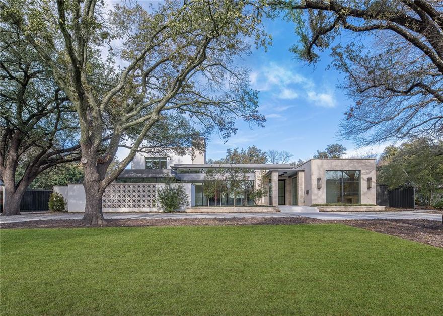 This custom home offers luxurious living on a .58-acre lot with lush landscaping and mature trees. Designed by SHM Architects and built by Faulkner Perrin Homes, the residence features 5 bedrooms, 5.3 baths, white oak floors, and walls of windows that fill the interiors with natural light. The chef’s kitchen boasts Danby marble on two large islands, countertops, backsplash, and a separate prep kitchen, along with top-tier Wolf, Sub-Zero, and Bosch appliances. A wet bar with a Sub-Zero wine refrigerator completes the space. The main-level primary suite features a fireplace, backyard access, dual closets, and a spa-inspired bath. Flexible office spaces with custom built-ins provide private retreats, while the utility room includes space for an extra refrigerator and a dog-washing station. Upstairs, you’ll find three en-suite bedrooms, a mirrored fitness room, a game area, and an unfinished space ready for a home theater or guest quarters. The outdoor living area is ideal for year-round use, with a fireplace, automatic screens, and heating. Modern amenities include a Generac generator system, an Elan audio visual operating system, and Lutron lighting and shades. A three-car garage with a drive-through option and electric charging plugs completes this meticulously designed home.