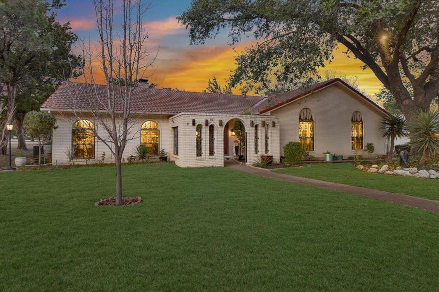 Beautiful modern hacienda-style home backing to a lush greenbelt with peaceful park views. This distinctive one-story Spanish-style residence blends timeless architectural charm with thoughtful functionality and warm design elements throughout. From the moment you arrive, you’ll notice the classic arched windows, decorative wrought iron accents, Spanish tile roof, and inviting curb appeal that set this home apart.  Inside, the home features a spacious open floorplan with multiple living and dining areas, perfect for both everyday living and entertaining. Flooring includes authentic Saltillo tile, rich hardwoods, and plush carpet. The expansive living room showcases a vaulted ceiling and a stunning raised-hearth stone fireplace, creating a grand yet welcoming atmosphere. A second fireplace adds comfort and ambiance to the private primary suite, which also includes an ensuite bath and walk-in closet. The kitchen is designed for both style and practicality, offering built-in cabinetry, eat-in dining, ample counter space, and views of the surrounding greenbelt. This home was thoughtfully designed with accessibility in mind and includes handicap-accessible bathrooms, zero-entry walk-in showers, wide doorways, and accessible kitchen and bedroom features, making it ideal for a variety of lifestyles.  Step outside to enjoy the tranquil setting with adjacent green space and park views, offering a sense of privacy and connection to nature. The community is well maintained and offers exceptional amenities including a clubhouse, swimming pool, jogging and bike paths, tennis courts, sidewalks, and landscaped common areas. HOA dues include full use of facilities. Immaculately clean, move-in ready, and full of character, this rare property offers comfort, charm, and convenience in a highly desirable setting. A truly unique opportunity to own a home with enduring style and thoughtful design.