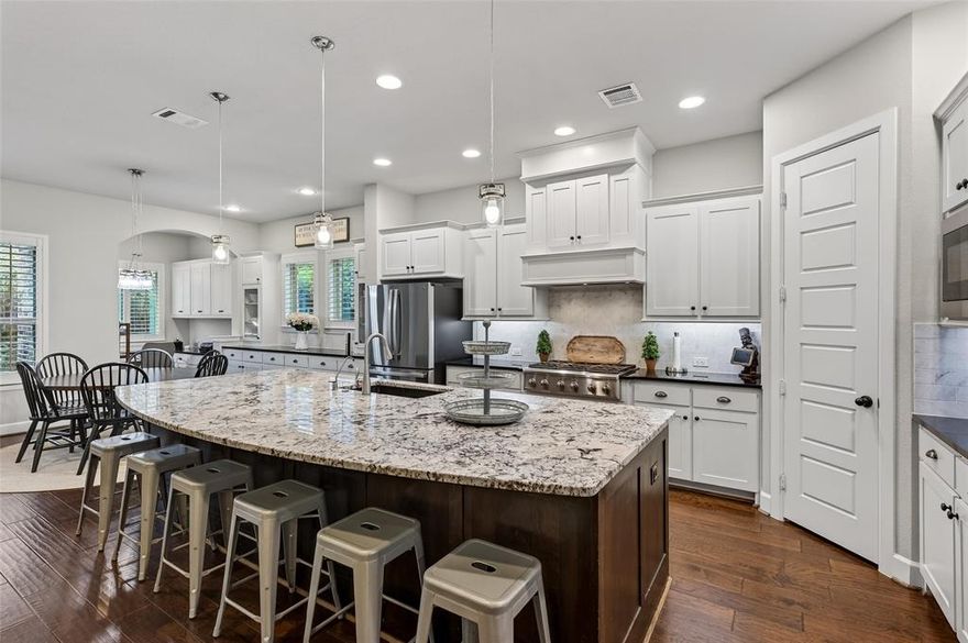 Stunning North facing, upgraded 5-bedroom, 2-story home with a 3-car garage located in the heart of McKinney in highly sought-after Stonebridge Ranch. Situated in Wynn Ridge Estates, one of the newer sections of the community, this home offers the feel of newer construction with a flexible and thoughtfully designed floorplan. A spacious first-floor secondary bedroom with ensuite bath and private patio access is ideal for a mother-in-law suite or multi-generational living. From the moment you enter, you’ll notice elevated finishes including engineered wood floors, designer lighting, wide crown molding, and light, bright interior paint. The chef’s kitchen is a showstopper featuring an oversized granite island, stainless steel appliances, double ovens, pendant lighting, and a timeless marble subway tile backsplash. A built-in coffee bar and dedicated charging station with desk create a functional space for everyday organization. The private primary suite is tucked at the back of the home and offers a spa-like bath with dual vanities, a frameless glass shower, freestanding soaking tub, and spacious walk-in closet with great lighting and a built-in mirror. A versatile office with custom built-ins sits at the center of the home and can function as a workspace, workout room, or craft area. Upstairs offers additional flexible living space plus three bedrooms. Enjoy the covered patio with dual fans and a backyard large enough for a pool. Additional features include two attic spaces with custom storage racks and a 3-car garage with epoxy floors and built-in cabinetry. Stonebridge Ranch residents enjoy exceptional amenities including pools, tennis, pickleball, and a clubhouse, with convenient golf cart access to both country clubs, Adriatica Village, and Westgrove shopping and dining.