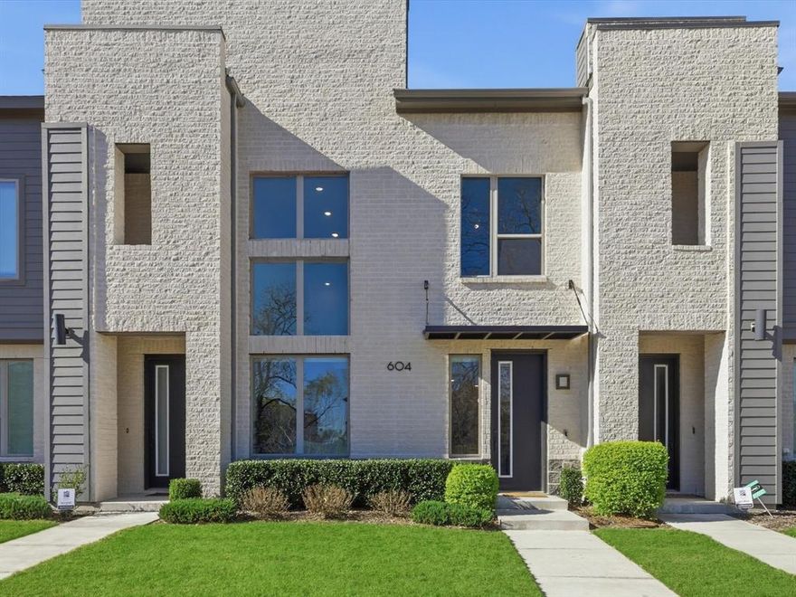 Premium greenbelt-facing, contemporary CB Jeni townhome situated within walking distance to shopping, dining, and coffee houses, and conveniently located for an easy commute throughout the DFW Metroplex. This impressive sophisticated home offers a true lock-and-leave lifestyle, showcasing clean lines and modern design throughout. Luxury vinyl plank flooring and awe-inspiring 21-foot ceilings welcome you into the open-concept first floor, where the living, dining, and kitchen spaces flow effortlessly. The spacious living room features stunning, oversized windows with electric shades that flood the home with natural light and a unique under-stairs nook, perfect for furry friends or additional storage. Fall in love with the fully equipped gourmet chef’s kitchen, equipped with a top-of-the-line Wolf gas range, Bosch Dishwasher, Quartz counter-tops, an oversized island, and both upper and under-cabinet lighting. A sleek wrought-iron staircase leads to the second level, where two split bedrooms provide ample privacy along with a versatile landing area. The spacious primary suite is a true escape, featuring a custom brick accent wall and a luxurious bath with dual sinks with Quartz counter-tops, a large walk-in shower with bench seating, and a generous walk-in closet. The secondary bedroom offers an ensuite bath and walk-in closet, making it perfect for guests or a flexible multi-purpose space. The two-car garage has epoxy floors and 220v outlet, ready to be set up for EV charging. Views of the tree filled greenbelt, just steps from your front door, give you a peaceful backdrop as you enjoy the convenience of low-maintenance living with easy access to major highways and all the amenities this desirable location has to offer.