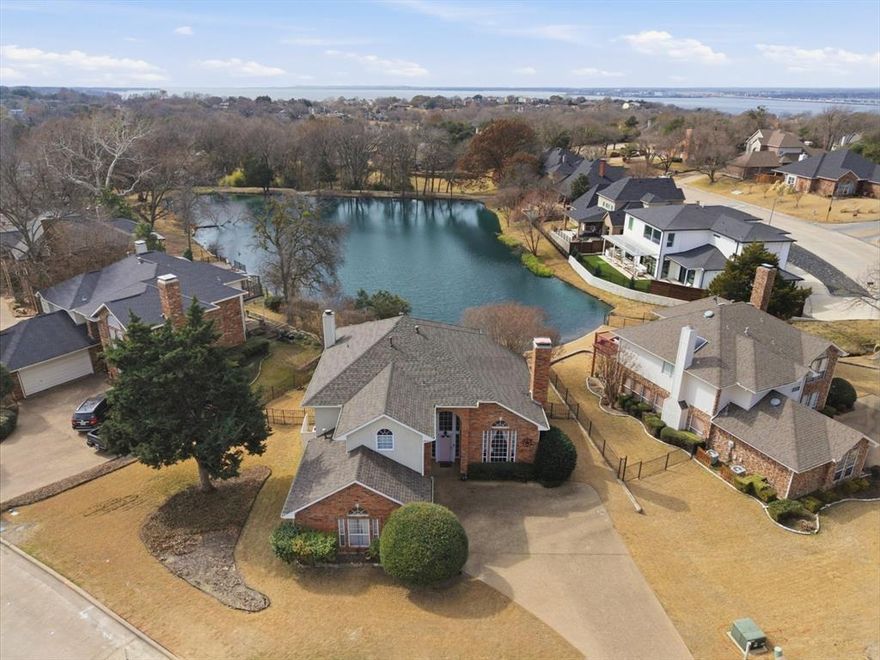 Wake up to peaceful water views in this custom brick home perfectly positioned on Blue Heron Pond in the desirable Chandlers Landing community. Offering a rare combination of scenic surroundings and everyday convenience, this property delivers a relaxed lakeside lifestyle just 30 minutes from Downtown Dallas. Designed with an open layout and soaring ceilings, the home provides generous storage and flexible living spaces ideal for both entertaining and quiet evenings at home. Two fireplaces create warm, inviting gathering areas throughout the main living spaces. The updated kitchen is a standout feature, showcasing modern finishes and a dramatic wall of windows that overlook the pond, filling the space with natural light and offering serene water views while you cook or entertain. The seamless connection between kitchen and living areas enhances the home’s airy, open feel.The spacious primary suite serves as a private retreat with its own balcony—perfect for taking in breathtaking sunset views over the water. The en-suite bath includes dual vanities, a soaking tub, separate shower, and a large walk-in closet. A screened patio extends from the family room, creating a comfortable outdoor living space where you can enjoy the backyard oasis and tranquil pond setting year-round.
Residents of Chandlers Landing enjoy gated security with a guard, community pools, tennis courts, clubhouse, Restaurant, bar, marina, private beach, boat ramp, fishing, scenic trails, and neighborhood dining—making this more than a home, but a true lake lifestyle experience!