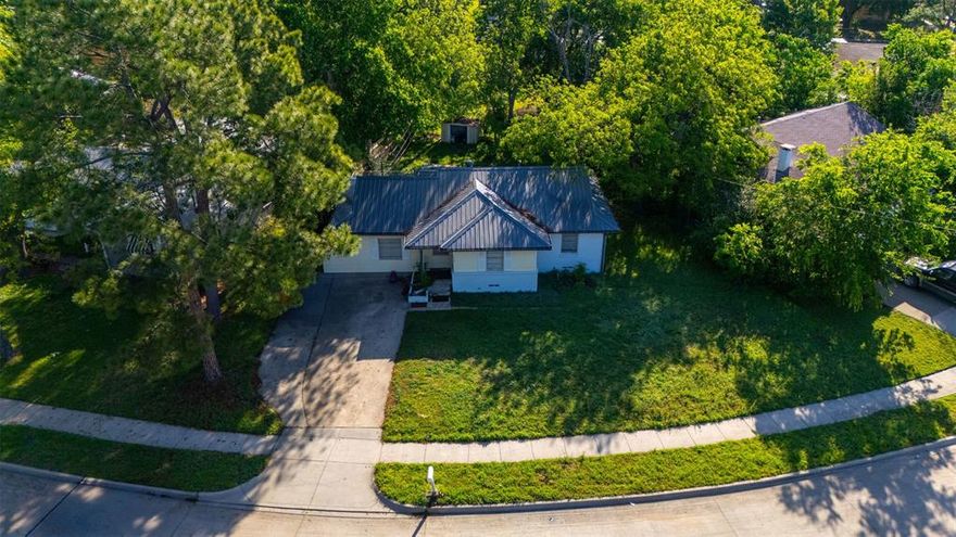 SELLERS ARE MOTIVATED! Bring us an offer! Tucked beneath a canopy of mature trees, this charming ranch-style home offers a peaceful retreat with tons of character. The metal roof, expansive green lawn, and long driveway create excellent curb appeal from the moment you arrive. Inside, you'll find a mix of hardwood and luxury vinyl plank flooring throughout, with exposed wood beam ceilings adding warmth and charm. The updated kitchen features gray shaker cabinets, subway tile backsplash, dark granite countertops, and a gas range — perfect for the home chef. Spacious bedrooms offer flexibility for any lifestyle, and the layout flows naturally for everyday living. The aerial view showcases just how lush and private this lot truly is, surrounded by mature trees that provide shade and seclusion. A fantastic opportunity for owner-occupants and investors alike — don't miss out!