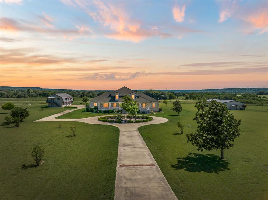 Located just west of Clifton on paved FM 182, this 7 acre estate offers privacy in Bosque County. Only 8 miles from Clifton, with a hospital, shopping, dining, and schools, the property is conveniently located, offering 45 minutes to Waco and 2 hours to Dallas–Fort Worth.

The custom Colonial-style home, built in 2000, features a roundabout drive and grand two-story design with approx. 3,620 sq. ft. on the main level and 1,715 sq. ft. upstairs. The first floor features a formal living and dining area, a spacious kitchen equipped with double ovens, an electric range, and a commercial-size refrigerator & freezer, as well as a large family room. Also on this level are two bedrooms, one of which is used as an office, an oversized laundry room, and the primary suite with two full bathrooms, one featuring a clawfoot tub and the other a walk-in shower.

Upstairs, the property offers five bedrooms and two bathrooms. Covered front and back porches capture sweeping views of the hillside.
Additional improvements include a four-car garage with a 1,800 sq. ft. apartment with 2BR & 2BA and a 3,200 sq. ft. metal shop with a holding tank. Two water wells and a septic system service both the home and apartment.

Surrounded by large ranches, this property offers a blend of privacy, space, and accessibility, an ideal retreat for those seeking a serene country lifestyle within easy reach of Clifton and the greater Bosque County area.