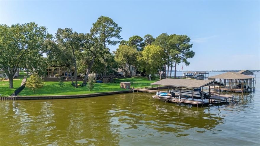 Welcome to your dream lake house! This beautifully updated home greets you with instant lake views as soon as you enter through the spacious living room. The kitchen is a chef’s delight with quartz countertops, stainless steel KitchenAid appliances, and two dining areas—perfect for entertaining. Durable luxury vinyl plank floors run throughout, ideal for pets and lake days. The primary retreat offers breathtaking lake views, a cozy sitting area, dual closets (one currently a bunk room), and a spa-like bath with a garden tub and separate shower. Freshly painted and meticulously maintained, this home also boasts upgraded underground PVC plumbing in 2024. Step outside to an enormous back deck with space for everyone—featuring a built-in treehouse, hammock, tree swing, and fire pit. Enjoy lake life with your private dock equipped with a boat lift, three jet ski lifts, and plenty of room to swim, fish, or play.