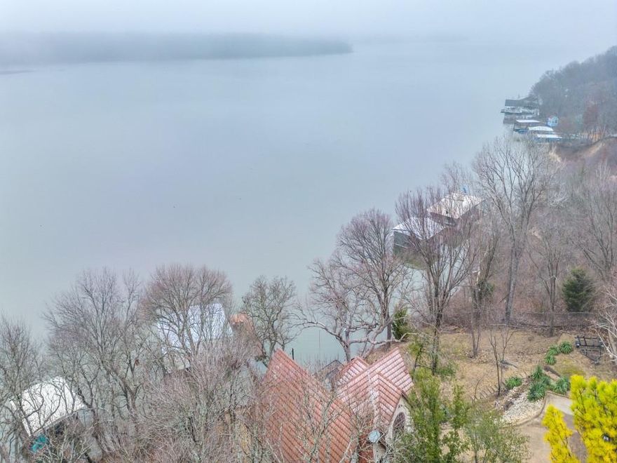 Charming Lakefront Retreat – Quiet and private lakefront location with calm waters and minimal boat traffic.
Stunning Water Views from Every Room, Large Dock, Enclosed Boathouse & Outdoor Fire pit – Perfect for VRBO! Escape to your private oasis with this beautiful lakefront home, just steps from the water’s edge. This 3-bedroom, 2-bathroom retreat offers breathtaking lake views from every room, making it ideal for relaxation and adventure. Inside, the open-concept living space is filled with natural light, featuring large windows that showcase the sparkling lake. The brick fireplace adds warmth and charm, perfect for cozy evenings. The spacious kitchen includes a breakfast bar, ample cabinet space, and a wine refrigerator, blending function and comfort. Each bedroom offers serene water views, ensuring a peaceful retreat at any time of day. Outdoor living is unmatched with two expansive decks—the upper deck is perfect for morning coffee, while the lower deck provides easy backyard and water access. A boater’s paradise, the property includes a large dock and enclosed boathouse, ideal for storing watercraft and gear. The backyard is designed for entertaining, featuring a large outdoor firepit and sitting area, perfect for gathering under the stars. Nestled in a secluded, nature-filled setting, this home offers privacy and tranquility, making it a fantastic option for full-time living or a vacation retreat. A proven VRBO success! Whether you’re looking for a personal getaway or an income-producing rental, this home delivers the perfect balance of comfort, nature, and adventure. Schedule your private tour today!