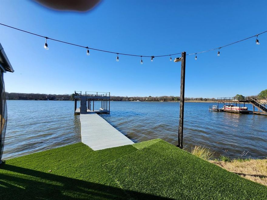 Put on your flip flops and come enjoy the lake and the beautiful open water view! This waterfront home is nicely furnished and ready for a new owner. Open living, dining and kitchen is perfect for gatherings or just enjoying the peaceful lake life. The master is large and separate from other 2 beds, opens out onto the screened in deck with a beautiful water view. Enjoy countless good times on your deck, in the hot tub, or out on the water boating.  Recent boathouse has sitting area, upper deck, jet ski lift, and boat lift. Stainless appliances, laminate flooring, and so many more great features. Owner has had good income from VRBO rental. Seller will negotiate concessions.  All furnishings can be purchased for additional cost