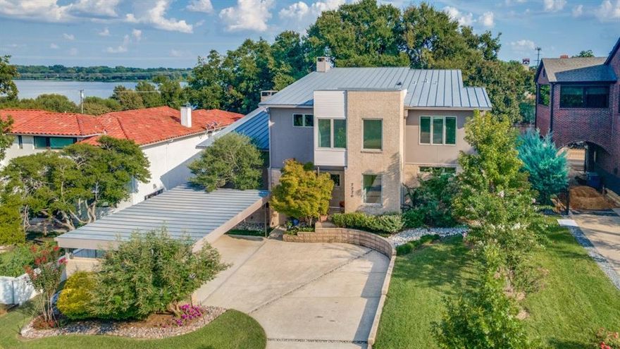 On one of Lakewood's most prestigious street. This Modern Contemporary offers a front seat to the shimmering beauty of White Rock Lake. The uniqueness of seeing daily lake views, unbeatable access to the shoreline and its vibrant wildlife makes this residence truly one of a kind. A bold sculptural drive-up makes an unforgettable first impression. While inside, the atmosphere balance sleek modern amenities with inviting warmth.  Fresh paint accents the home’s clean lines and open-concept floor design. A chef’s kitchen with wet bar, quartzite countertops, anchors the main living space complemented by custom  grain matched walnut cabinetry. A separate entrance catering kitchen is adjacent to the media room Every detail has been designed to impress. Museum-quality walls and soaring ceilings provide the backdrop for art of almost any size. At the heart of it all is a showstopping, climate-controlled 600-bottle wine library—complete with rolling ladder and views of the pool and lake beyond—designed for the serious collector who loves to entertain and protected by a full-home Generac generator. Floating, glass-railed staircases connect each level, adding understated drama throughout. Almost every room in the home captures a view, with the primary bedroom—located on the main floor—enjoying especially stunning sightlines. The primary bathroom brings the beauty of the outdoors inside with a serene retreat, featuring grain-matched cabinetry and thoughtfully designed closets for everything. Outside is a private retreat: a luxurious pool framed by an expansive Ipe wood deck, freshly stained to complement the architecture. The setting is ideal for relaxing afternoons and lively summer gatherings. Just beyond, White Rock Lake offers beautiful views and easy access to trails, sailing and birdwatching, while the historic fish hatchery is just around the corner—offering a forest at your fingertips  A daily invitation to unwind.. This is more than a home—it’s a modern masterpiece.