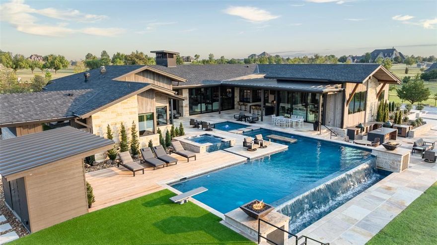 Less than an hour from Dallas, in Rockwall County—Texas’ smallest yet wealthiest county—this lakeside community draws those seeking space, privacy, and an elevated lifestyle. Set on over five acres within a gated subdivision, further secured by its own private entrance, this estate was crafted as the builder-developer’s personal residence and stands as a masterclass in Texas Modern design. Defined by clean architectural lines, organic textures, and expansive walls of glass, every detail is intentionally curated to blend sophistication with ease, offering enriched daily living and effortless entertaining.
The 5,649 SF main residence showcases a gourmet kitchen and grand living area anchored by a striking linear stone-framed firebox, where views spill seamlessly outdoors. A dedicated fitness and wellness space opens directly to fresh air and poolside vistas, creating harmony between activity and retreat. From the upper level of the 1,486 SF two-story guest house-design studio, gather next to the fireplace and enjoy sweeping views of the estate and its grounds. The property also includes a 1,497 SF garage with workshop—ideal for creativity, hosting, or collection storage.
Outdoor living unfolds across multiple gathering spaces, from expansive covered patios and full kitchens designed for celebrations to sleek lounging areas by the infinity-edge pool with in-pool bar seating. Play pickleball on your private court, watch the kids bounce on the in-ground trampoline, or wander to the private pond where casting a line offers simple joy. Take a ride by horse or ATV on trails within the subdivision. As the sun sets, gather around a fire pit nestled beneath manicured trees by the creek, sharing stories under the Texas sky.
This is more than a home—it’s a luxury lifestyle designed for connection, recreation, and retreat. With Dallas less than an hour away, every convenience is within reach while you revel in the privacy of your own sanctuary.
