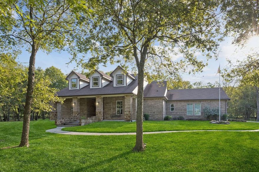 Nestled on 3.4 wooded acres at the end of a quiet cul-de-sac, this property delivers the privacy of country living with the finish-out of a luxury custom build. The home is set back nearly 300 feet from the road, surrounded by mature trees, and designed around an open-concept floor plan with a thoughtful 3-way split bedroom layout. Inside, you’ll find the kind of details that instantly stand out: oversized 8-ft doors, crown molding throughout, custom ceiling treatments, plantation shutters, and upgraded BMC Low-E argon gas windows. The kitchen is an entertainer’s dream—granite counters, double ovens, a custom backsplash, and a massive island that flows straight into the living and dining spaces. A cozy pellet stove in the living room adds character, while the primary suite feels like a retreat with a spa-style slate shower, soaking tub, and walk-in closet. Step outside and the lifestyle continues—an extended 30x16 covered patio with full outdoor kitchen, pull-down shades, and plenty of space for both dining and lounging. The detached 35x31 garage has RV parking, loft storage, steam shower, and endless potential as a workshop, gym, or hobby space. If you’re looking for a property that balances privacy, function, and high-end style—this one checks every box. Minutes from I-30 for easy access into Rockwall or Dallas, yet far enough out to truly unwind.
