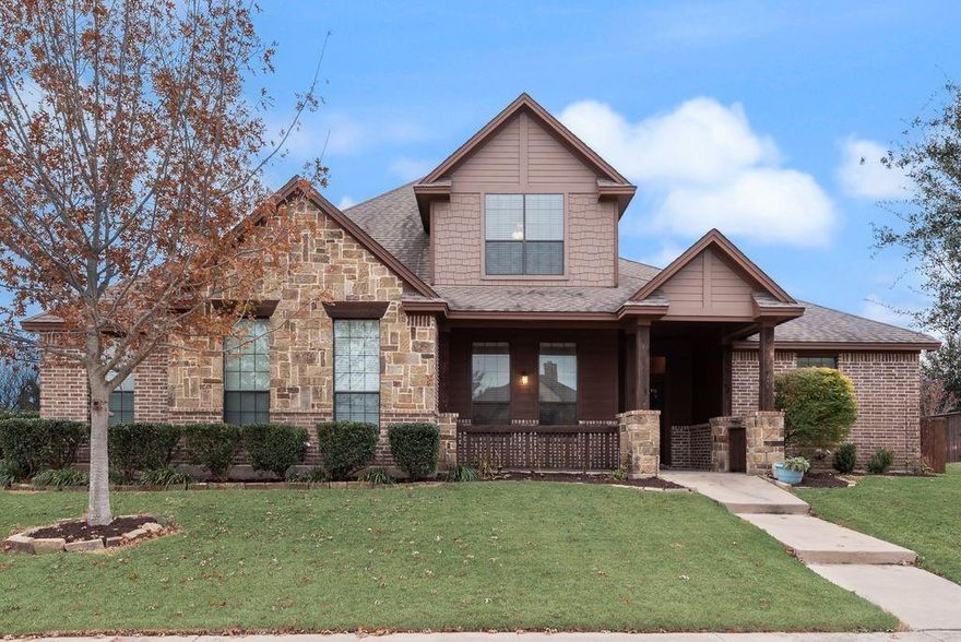 Set on a generous .35-acre lot, this beautifully crafted 4-bedroom, 3.5-bath home offers the perfect balance of thoughtful design and everyday comfort. A charming covered front porch creates an inviting first impression and welcomes you into an open, light-filled floor plan accented by rich tile-wood flooring throughout the main living areas.

The spacious living room is anchored by a striking stone fireplace with gas logs, creating a warm and inviting backdrop for both quiet evenings and lively gatherings. The kitchen serves as the heart of the home, featuring granite countertops, a large island with breakfast bar seating, stainless steel appliances, an electric cooktop, and a walk-in pantry—designed for both functionality and style.

Just off the entry, a private study provides an ideal work-from-home space. The primary suite is conveniently located on the first floor and offers a true retreat with dual vanities, a separate soaking tub and shower, and an oversized walk-in closet with direct access to the laundry room for added ease. A secondary bedroom on the main level adds flexibility for guests or multigenerational living.

Upstairs, two additional bedrooms are complemented by a spacious game room, perfect for movie nights, play space, or an additional living area. Step outside to enjoy the expansive backyard and covered patio—ideal for entertaining, relaxing, or creating your own outdoor oasis.

A mudroom and three-car garage complete this well-appointed home, delivering smart storage and everyday convenience in all the right places.