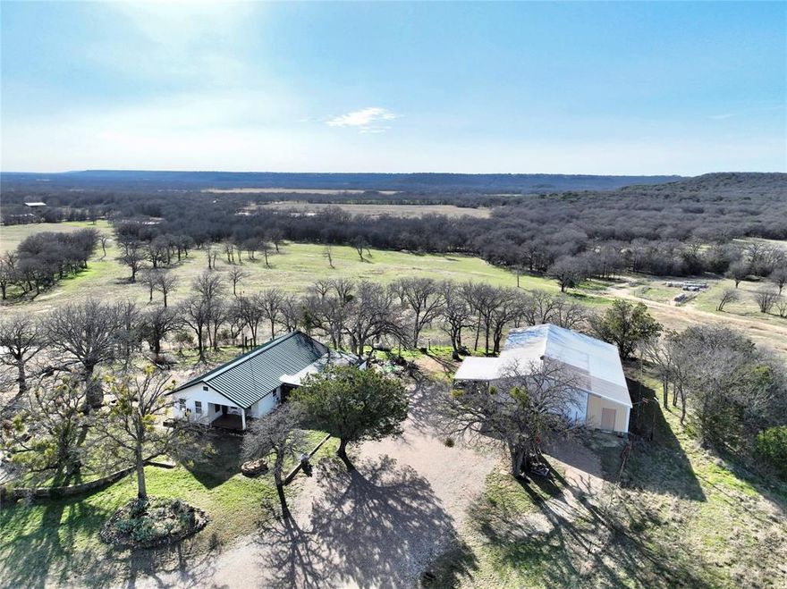 Rare 93+- Acre TX Retreat  Expansive Acreage, Multiple Ponds & Epic Views, Only 30 Minutes from Ft Worth. Seize this exceptional oppty to own a true rarity in today's N Texas market. 93 sprawling ac of prime rural land, just a quick 30 min drive W of Fort Worth offering easy access to the DFW Metroplex while delivering the privacy, space, & natural beauty that's increasingly hard to find so close to the city. Properties of this size & quality, with this level of proximity, are scarce as development pressures push larger acreages farther out. Perched on a prominent hill, the inviting 1,616 sf 2 bed 1 bath farmhouse. A cozy base for weekend escapes or FT living. Enjoy sweeping, unobstructed panoramic views southwest to the dramatic Palo Pinto mountains and limestone ridges & oak-covered slopes creating a stunning, ever-changing backdrop that captures the essence of authentic TX Hill Country charm. The rolling terrain is blanketed in productive coastal Bermuda grass, mature oak trees for shade & wildlife appeal. Water features abound with 4 stocked ponds ideal for fishing, recreation, & attracting game, plus a scenic wet weather creek that adds seasonal charm & enhances the property's natural appeal. The entire acreage is fully fenced, ready for livestock, horses, hunting, or simply enjoying wide open seclusion. Practical upgrades include a generous 40x43' shop with dedicated tractor parking for equip & projects, plus a storm shelter for added security during unpredictable TX weather. Currently cherished as a peaceful weekend getaway to escape the big-city, this turnkey property combines convenience, tranquility, & abundant outdoor amenities making it perfect for a family homestead, recreational retreat, or investment in rare Metroplex adjacent acreage. Unwind amid nature's splendor with fishing ponds, creek views, rolling hills, & those unbeatable mountain vistas all without sacrificing quick access to Ft Worth's amenities. Rare opportunity in this sought after area.