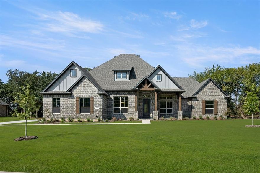 MLS# 21004180 - Built by Sandlin Homes - Ready Now! ~ Our Wildwood plan offers a spacious and thoughtfully designed layout featuring four bedrooms, three bathrooms, a private study, and a three-car garage. This stunning home showcases a harmonious blend of design elements, including a mix of painted and stained cabinetry, satin brass and black hardware, and quartz countertops.    The kitchen is a standout with its blue-accented island, wood hood vent, glossy backsplash, and elegant pendants over the island. The blue-gray tiled fireplace compliments the island, creating a cohesive and stylish focal point. Additional upgrades include premium carpet, hexagon-pattern tile in the utility, and luxurious tile selections in both the primary and secondary bathrooms.    Finishing touches such as J-channel black-framed mirrors in the primary, bronze plumbing fixtures, and high-end materials throughout to elevate the home’s aesthetic and functionality.