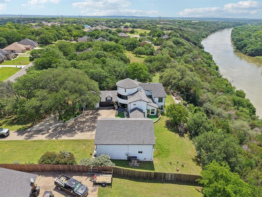 Exquisite luxury meets tranquil outdoors with this stunning home located on a bluff overlooking the Brazos River and a serene valley. Homes like this come available once in a lifetime! The Details: Drive up to the entrance and you are greeted by a beautiful rustic metal gate for the ultimate in privacy and security. The front of the 1.72 acres of mature treed land is surrounded by an elegant stone wall enhancing your private oasis and giving you additional security. As you come down the extended driveway to the main house you will note the amazing elevated view of the Brazos River and the valley below! Entire property has large mature and blooming trees throughout. Main house is 5342 square feet with 3 main levels. A 4th level has steps off the balcony leading to a unique domed play room for the kids! 5 bedroom, 5 and a half bath, office, breakfast nook, and separate dining area. Main house features a full oversized 3 car garage. Additionally you have 2 walk out balconies and simply amazing views out the back of the house of the Brazos River! Guest house has an attached RV garage with 14 foot insulated walls. Guest house is a 1 bedroom, 1 bath, living, and kitchen totaling 1107 square feet with quartz flooring. The Finer Details Main House: A chefs dream kitchen with views out to the River as you cook. Formal dining is situated perfectly to enjoy your meal with tranquil views of the water and valley below. Main living features a beautiful wood burning fireplace. Master suite is simply stunning with ample room and a separate Master retreat overlooking the River. Upgrade wood flooring throughout and each bathroom features an oversized walk in shower. Home is perfectly situated near the back gate of Pecan Plantation. A short drive in your golf cart to the main clubhouse, marina, boat slips, and all amenities offered. Main house and guest house have had numerous recent updates completed. This is a truly unique home with captivating views and ample room for any buyers!