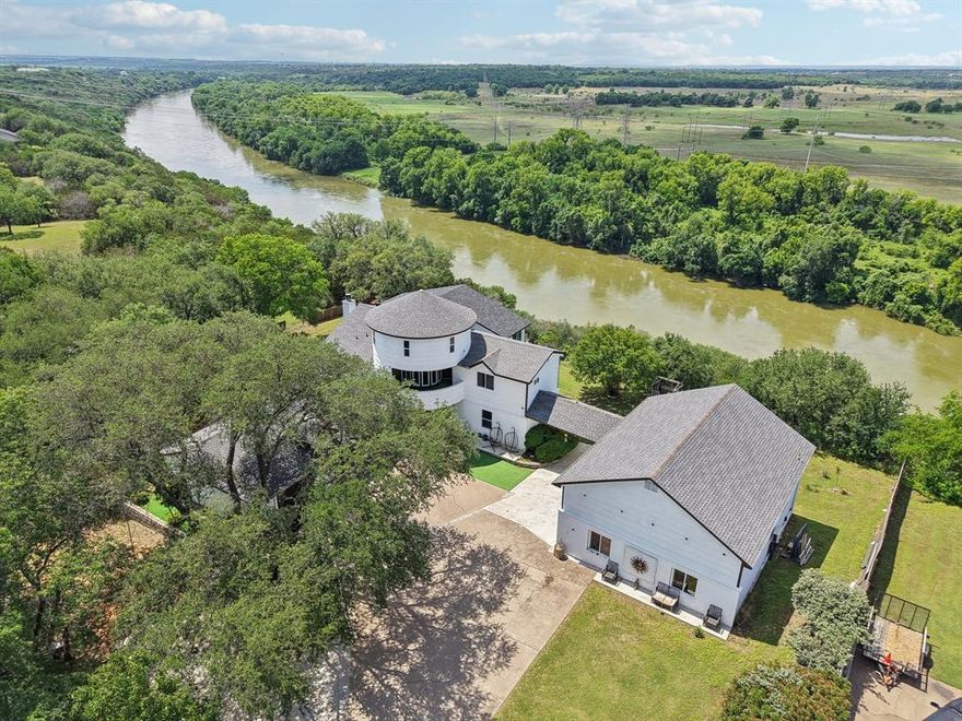 Exquisite luxury meets tranquil outdoors with this stunning home located on a bluff overlooking the Brazos River and a serene valley. Homes like this come available once in a lifetime! The Details: Drive up to the entrance and you are greeted by a beautiful rustic metal gate for the ultimate in privacy and security. The front of the 1.72 acres of mature treed land is surrounded by an elegant stone wall enhancing your private oasis and giving you additional security. As you come down the extended driveway to the main house you will note the amazing elevated view of the Brazos River and the valley below! Entire property has large mature and blooming trees throughout. Main house is 5342 square feet with 3 main levels. A 4th level has steps off the balcony leading to a unique domed play room for the kids! 5 bedroom, 5 and a half bath, office, breakfast nook, and separate dining area. Main house features a full oversized 3 car garage. Additionally you have 2 walk out balconies and simply amazing views out the back of the house of the Brazos River! Guest house has an attached RV garage with 14 foot insulated walls. Guest house is a 1 bedroom, 1 bath, living, and kitchen totaling 1107 square feet with quartz flooring. The Finer Details Main House: A chefs dream kitchen with views out to the River as you cook. Formal dining is situated perfectly to enjoy your meal with tranquil views of the water and valley below. Main living features a beautiful wood burning fireplace. Master suite is simply stunning with ample room and a separate Master retreat overlooking the River. Upgrade wood flooring throughout and each bathroom features an oversized walk in shower. Home is perfectly situated near the back gate of Pecan Plantation. A short drive in your golf cart to the main clubhouse, marina, boat slips, and all amenities offered. Main house and guest house have had numerous recent updates completed. This is a truly unique home with captivating views and ample room for any buyers!