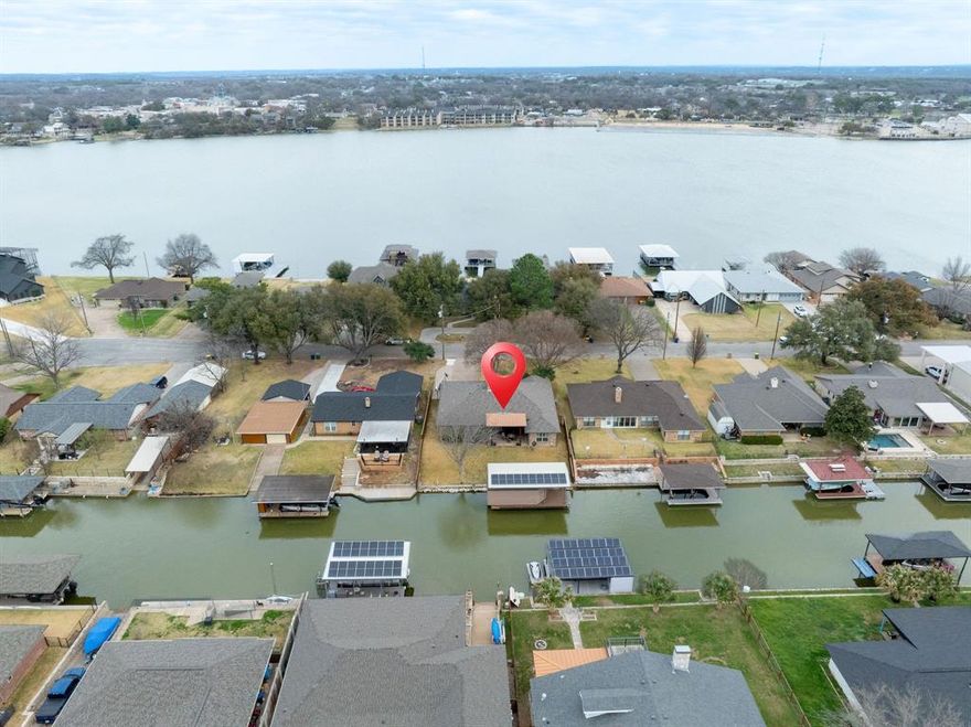 Beautifully updated lakefront home in The Shores addition of Granbury, no City Taxes, outside City limits, no HOA! Can be an Airbnb! This move in ready property features wood look ceramic tile flooring, fresh interior and exterior paint, and plantation shutters throughout. The open layout offers vaulted ceilings and abundant windows, filling the home with natural light and showcasing peaceful lake views. The spacious kitchen is perfect for entertaining with new quartz countertops, stainless steel appliances, and a large island. A reverse osmosis water drinking system adds extra convenience. The primary suite includes a newly updated bath with quartz countertops, an oversized shower, and a lighted vanity mirror. Step outside to a 21x18 covered porch under a cedar pergola that is ideal for relaxing or entertaining lakeside. The impressive 18x35 dock features a 10.5x25 boat slip, 30-ft touchless remote-controlled boat cover, 4,000 lb boat lift with V hull cradle, and a 4.75 kW solar system. Additional upgrades include a new HVAC system, a roof just 6 years old, and a sprinkler system powered by a 220V 1.5 HP pump with low-cost lake water usage approx. $53 per year. Enjoy lake living at its best with modern updates, energy-efficient features, and exceptional outdoor amenities!