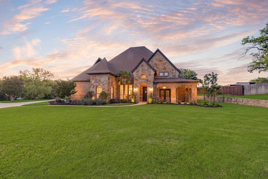 Nestled on just over an acre, this stunning estate offers the perfect blend of luxury, comfort, and privacy. Showcasing beautiful brick and stone curb appeal, a charming wrap-around front porch, and a side-entry 3-car garage, the home makes a lasting first impression. Inside, you’ll find a thoughtfully designed layout featuring 4 bedrooms on the main level, a formal dining room ideal for entertaining, and a dedicated executive study with built-ins. The spacious family room is anchored by a striking stone fireplace and flows seamlessly into the chef’s kitchen, complete with a large seated island, quartz countertops, double ovens, 6 burner gas cooktop, and refinished cabinetry—perfect for everyday living and hosting alike. The primary suite is a true retreat, offering a cozy sitting area and a relaxing ensuite with dual vanities, jetted tub, walk-in shower, and a generous walk-in closet. Upstairs, enjoy endless entertainment in the game room and media room with tiered floor. Freshly painted interiors and new waterproof floors add a bright, updated feel throughout. The Control4 Home Automation system integrates your devices and the alarm system provides peace of mind. Step outside to your private backyard paradise, where a covered patio with fireplace, outdoor kitchen with gas grill and bar seating, and a sparkling heated pool are surrounded by lush green space and mature shade trees—ideal for relaxing or gathering with friends and family. Perfectly positioned near Westlake’s prestigious financial district, the exclusive Vaquero Club, and just minutes from Southlake Town Square, this exceptional property offers luxury living in a prime location. Bonus: horses and livestock are permitted!