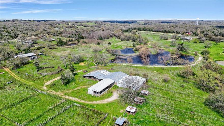 This 26-acre property in Mountain Springs, located along FM 372, offers a range of possibilities. It features three 40 x 60 barns, a 30 x 60 breeding area, multiple turn-out pens, and four loafing sheds. Previously used as a breeding facility, the property has great potential with some updates. The land's rolling terrain provides beautiful views, and a creek running through the property feeds two large ponds. While the existing home needs to be demolished, it boasts a prime entrance on FM 372. Viewings are available by appointment through the gate next to the house.
