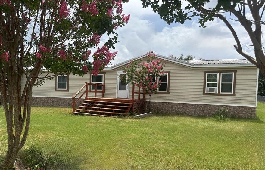 Discover the perfect blend of country living and convenient comfort with this charming mobile home nestled on 5 unrestricted acres. Imagine waking up to peaceful mornings and enjoying the freedom to create your dream lifestyle on this expansive property.
This spacious 4-bedroom, 2-bath home offers a fantastic opportunity for comfortable living, with plenty of room to grow and customize. Step inside to find a welcoming interior with 2 LA, 2DR, wood wood-burning fireplace, a large island, spacious bedrooms, and an amazing covered rear deck. 
Outside, the possibilities are endless. The 5.79-acre lot provides ample space for gardening, raising animals, or simply enjoying the tranquility of nature. With 2 storage containers, a workshop, a large utility shed, and covered parking offers lots of storage potential. 
Located just outside the city limits, you'll enjoy a quiet rural setting while maintaining easy access to Hwy 287 and minutes from I-35 or I-45.