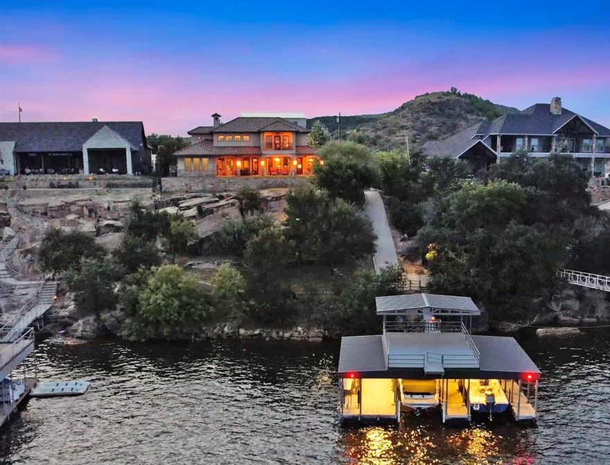 PK Westside – Gated Lakefront Retreat! Experience seclusion and privacy in this stunning luxury home with spectacular lake views.
This property features a two-story dock on deep water, complete with boat and PWC lifts, an extra-long swim platform, outdoor shower, and a fish-cleaning station. The home’s Boral roof, stucco exterior, and courtyard add to its distinctive appeal. Inside, the open great room, dining area, breakfast room, and kitchen all showcase breathtaking lake views. A soaring 20' floor-to-ceiling stone fireplace and hand-scraped wood flooring create warmth and character. Architectural details include wood-lined beamed ceilings, stone arches, and abundant custom cabinetry with glass fronts. Rare, exquisitely cut Taj Mahal Quartzite countertops with a striking backsplash & travertine flooring highlight multiple areas of the home. Wide doorways and accessible showers add comfort and convenience. The lakeside outdoor patio has an outdoor kitchen and a place for outdoor entertaining. The home offers three en-suite bedrooms plus a bunk room, ideal for guests. The primary suite has a coffee bar, double walk-in closets, an indoor and outdoor balcony to enjoy your peace & quiet before you start your day. An insulated 33' x 40' shop provides ample space for a boat, motorhome, tools, and recreational equipment. It features two 12' x 16' overhead doors plus a rear door opening to a covered patio. The 17' x 40' second floor is insulated and ready to finish into additional guest quarters, complete with its own deck  Additional highlights include: Whole-house water filtration system, Two hot water systems, including one on-demand, Multiple utility sinks, Shop pre-plumbed for a bathroom, Hidden concrete-lined safe room for valuables and storm protection, Space allocated for a future elevator if desired. This property is designed for both everyday luxury and lakeside adventure.