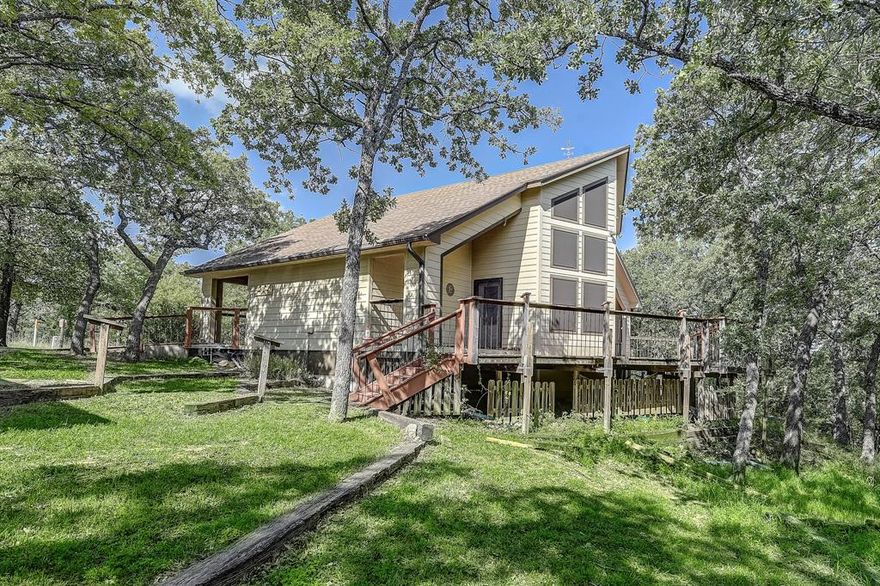 Discover the charm of this unique Ralph Lauren Cottage-inspired home, newly listed and ready for you to make it yours. This delightful residence features three generously sized bedrooms, including two master suites, providing ample space for family and guests alike. Each bathroom is thoughtfully designed with convenience in mind, highlighted by a walk-in shower equipped with body sprayers, ensuring a spa-like experience at home.

The heart of this home is a spacious kitchen, perfect for culinary enthusiasts. It boasts an island for additional counter space, copious amounts of cabinet storage, a double pantry, a smooth top stove, and unique custom cabinets including a mixer holder for the baking aficionado. The kitchen opens to an eat-in area, creating a perfect environment for intimate dinners or casual breakfasts.

Living spaces are accentuated by beamed cathedral ceilings and expansive windows framing the picturesque views of surrounding mature trees and an exquisite iris garden. Step outside onto the custom wood party deck, an ideal spot for entertaining or simply soaking in the serene landscape on the edge of two stunning golf courses.

Additional standout features include a She-Shed with air conditioning and electricity, providing a private retreat or an inspiring studio space. For convenience, the carport includes a workshop with power and water supply, and a large attic for extra storage. The property also includes a pad with a 30-amp supply space, accommodating a 28-foot recreational vehicle, and the deck is pre-plumbed for a hot tub installation.

With its captivating blend of functionality and style, this property is a rare find in a tranquil setting, inviting you to indulge in both comfort and luxury. Here, every detail is designed to contribute to a relaxed lifestyle while offering practical amenities to complement your everyday needs. Embrace this opportunity to own a piece of paradise approximately 1.5 miles to Lake Nocona.