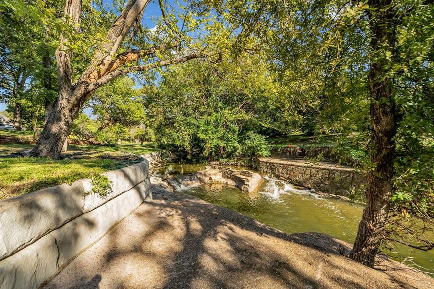 One of a kind ACTIVE CREEK. Enjoy the beauty and sound of an active creek at the rear of the property, enhancing this park-like yard with mature trees. shaded sitting areas, and private access to your own water source—a truly special outdoor setting. Whether you’re entertaining guests, unwinding at the end of the day, or letting the kids play, this serene retreat feels like an extension of the property.

Inside, the home has good bones with some updates, including Pella windows that frame peaceful views of the lush surroundings. Hardwood floors run throughout, complementing the generous living spaces and thoughtfully designed custom built-ins. The updated kitchen features granite countertops, stainless steel appliances, and a 5-burner gas cooktop—ideal for both everyday living and hosting.

The family room offers a cozy wood-burning fireplace that creates a warm and inviting gathering space. The oversized primary suite includes dual sinks, a corner shower, ample counter space, and custom storage. Secondary bedrooms are spacious and well-appointed, offering flexibility for family, guests, or a home office.

An oversized driveway provides parking for multiple vehicles, a boat, or a camper. Don’t miss this rare opportunity to own a creek-front property with an expansive yard in one of Farmers Branch’s most desirable neighborhoods.