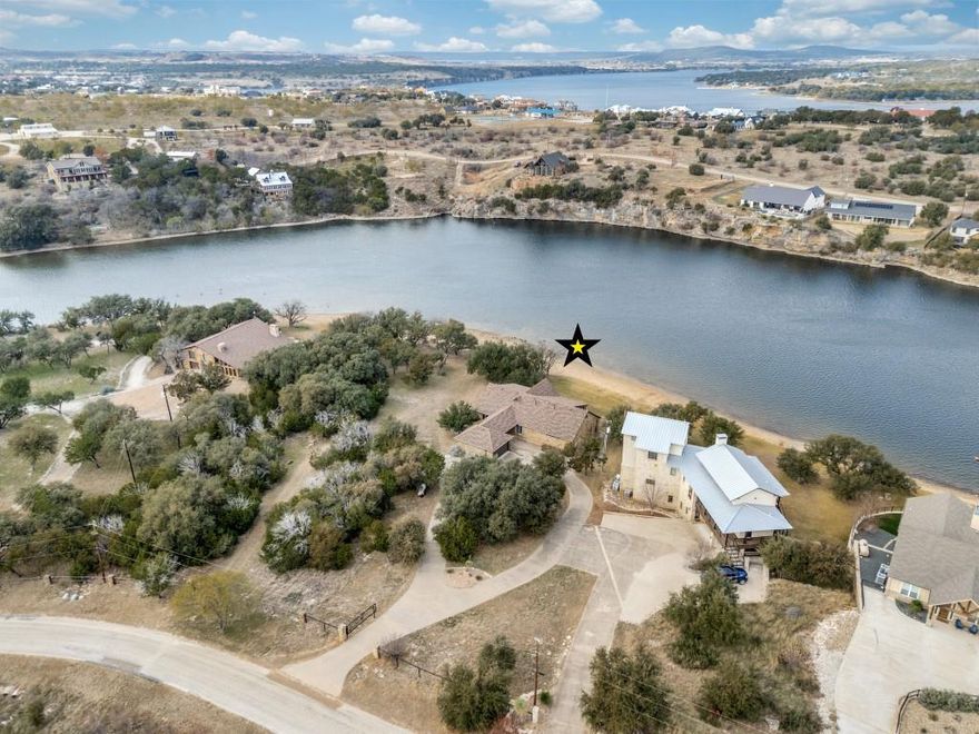 See to believe!  Enjoy this gently sloping lawn onto a rare sandy beach in smooth no-wake water, allowing you to beach your boat and watercraft just a short walk directly in front your home. From there, & from the elevated covered patio that runs the full length of the home, you have amazing views of famed Hells Gate & the surrounding bluffs, with front row seats to the spectacular Fourth of July fireworks, iconic Hell’s Gate cliff diving, & serene glassy deep water.  Built in 2012 to maximize the water features and efficiently use the interior space, the one-level ranch-style residence offers an open great room, dining, & kitchen with an architecturally compelling vaulted ceiling, anchored by a wall of windows across the length of the home, bringing the lake indoors year-round. Double glass entry doors, beautiful cabinetry, 8’ tall doors, rich wood floors, 7” baseboards & 10' high ceilings throughout the home show the home was built to a higher standard. The oversized primary suite features full lake views & the junior master bedroom offers a private en-suite bath; and generously sized bedrooms 3 & 4 share a third full bath. A spacious laundry and pantry room includes a 10’ long countertop, washer and dryer, and a second refrigerator, ideal for extra food & supplies for large gatherings. This resort-style property is accessed through an electronic gate at the road and features a concrete circular driveway winding through secluding trees. The garage connects to the home via a porte-cochère, which provides additional covered parking. The outdoor living area is fully equipped with a built-in grill, speakers, and television—perfect for entertaining and watching your family and guests’ activities across the lawn and in the water.  Keep your boat and waverunners a short ride away at Bluff Creek Marina (let them handle the hassles and expense of boat dock ownership!). All furnishings and water toys are available for purchase, offering a true turnkey lakefront lifestyle.