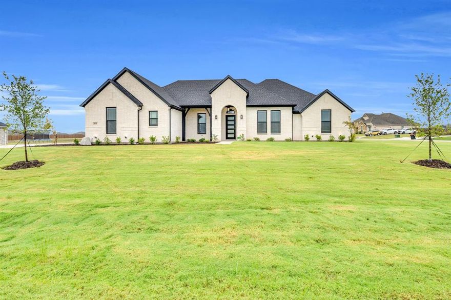 Welcome to Springside Estates in Waxahachie ISD! This stunning modern white brick home with cedar accents offers 4 bedrooms, 2 baths, and a versatile flex room that can serve as a study or game room, all within 2,487 sq. ft. per builder plans. Sitting on a premium corner lot, the property features an extended front patio and a spacious 3-car garage. Inside, the foyer welcomes you with 11-foot ceilings, leading to a large family room with engineered wood floors, a linear electric fireplace with a cedar mantle, and plenty of natural light. The gourmet kitchen is a chef’s dream, showcasing a curved wrapped island with quartz countertops, black pendant lighting, white custom cabinets, pots and pans drawers, and LG appliances, while the breakfast area offers a cozy dining space. The separate utility room is designed with upper cabinets and modern crystal black floor tile. The main bedroom boasts 10-foot ceilings, upgraded carpet, and a luxurious bath with a garden tub, dual quartz vanities, framed black mirrors, comfort-height toilets, and his-and-hers walk-in closets with built-in shoeboxes and upper racks. Secondary bedrooms also include walk-in closets, while the full bath offers a double vanity, matte black fixtures, and an upgraded tiled shower. Outdoors, the extended covered patio with a built-in brick wood-burning fireplace and electric hookup for a future TV is perfect for entertaining. Additional highlights include spray foam insulation, a smart home package with video doorbell and security, and 2inch faux wood blinds throughout.Ask about our Hometown Hero Incentive Program!