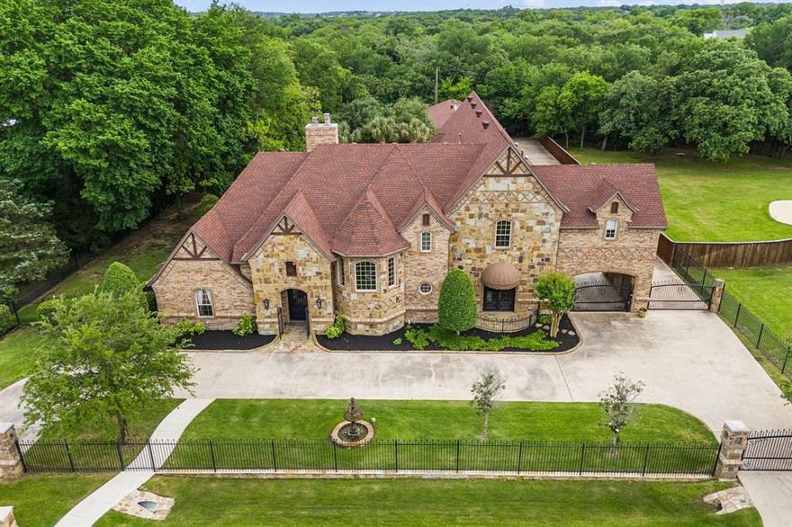 Welcome to this exquisite Tudor-style estate that blends old-world charm with modern luxury on a sprawling lot in the heart of Keller. Behind its striking stone façade and gated entry, this custom residence offers a rare combination of architectural elegance and highly functional amenities for both everyday living and entertaining. Inside, discover richly detailed interiors featuring soaring ceilings, hardwood floors, and a grand stone fireplace anchoring the expansive living area. The gourmet kitchen boasts granite countertops, dual islands, double ovens, and custom cabinetry. A dedicated theater room sets the stage for movie nights at home, while a separate mother-in-law suite offers ultimate privacy for extended stays or multi-generational living. The luxurious primary suite features a dual-head walk-in shower, an oversized walk-in custom closet with chandelier lighting, and serene backyard views. Outdoors, enjoy resort-style living with a sparkling pool surrounded by palm trees, a covered stone patio with built-in grill and fireplace, and beautifully landscaped raised garden beds ready for your green thumb. Car enthusiasts and hobbyists will appreciate the abundance of parking and garage space, including a covered RV carport with hookup and built-in utilities, four-car attached garage—complete with a dog washing station—and a detached three-car garage that features a lofted office space and a downstairs room with its own en-suite bathroom. Two on-site storage buildings provide abundant space for tools, toys, or seasonal décor, and a private well and well tank ensure irrigation independence. Additionally, the room currently being used as an exercise room can easily be converted into a third bedroom upstairs in the main house! Located in a quiet, tree-lined neighborhood with convenient access to local amenities, this home checks every box for those seeking luxury, functionality, and architectural beauty. Schedule your showing today!