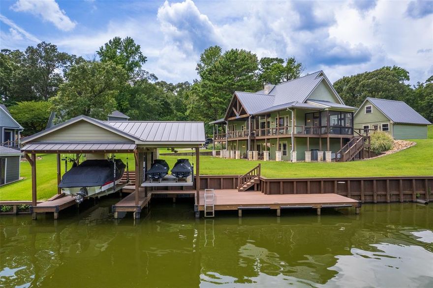 Welcome to 109 King Shore Blvd, a luxury waterfront retreat in Kings Country on Lake Cypress Springs. This nearly 4,000 sqft, FEE SIMPLE property on a cove offering calm waters, lake views, and a serene setting for full-time or weekend living. The home features four bedrooms total, with three offering private ensuite baths. The spacious primary suite is located on the main level and includes its own fireplace, a sitting area surrounded by windows, a jetted tub, and a walk-in closet. The main living room boasts floor-to-ceiling windows overlooking the lake, a stone fireplace, and wood flooring. The kitchen is designed for both functionality and entertaining, with granite countertops, a center island, and a butler’s pantry. A powder bath, screened porch, and covered deck complete the main level. Downstairs, you'll find two guest bedrooms with ensuite baths,along with the fourth bedroom, a game or media room, a kitchenette, a second laundry area, and an additional half bath. The home is equipped with smart features including Sonos surround sound, automated lighting, waterline leak detection, ADT security, two-zoned HVAC, two 75-gallon water heaters, and two laundry areas. Outside, enjoy a freshly painted exterior, new 2023 boathouse with Trex decking along with a newly installed retaining wall. A detached two-car garage and long concrete drive provide ample parking and storage. This home is being offered fully furnished with a few exceptions and includes a golf cart. Located in a gated community with a boat ramp, fishing piers, and tennis courts, this is a rare opportunity for turnkey luxury lake living in one of East Texas’s most desirable waterfront communities.