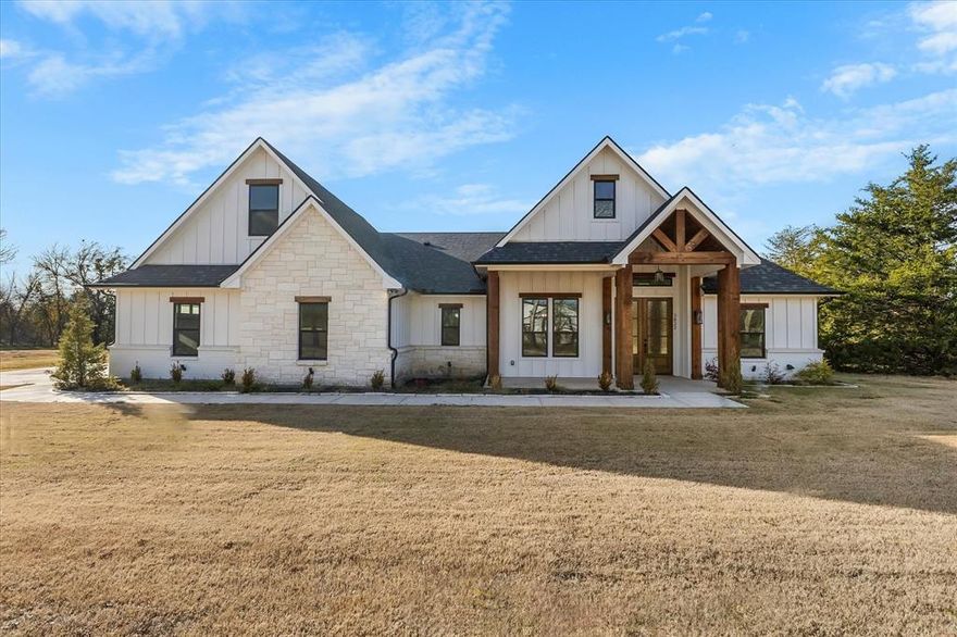 Farmhouse-inspired beauty on a 1 acre corner lot in the sought-after Whispering Winds community, offering peaceful country living off the beaten path in highly rated Caddo Mills ISD. This stunning home features a welcoming covered front porch with knotty alder double front doors that open to an open-concept living space showcasing luxury vinyl flooring, vaulted ceilings with cedar beam, floating shelving, and a dramatic floor-to-ceiling stone, wood-burning fireplace. A dedicated formal dining room or formal sitting area provides flexible space for entertaining or everyday living. The gourmet kitchen boasts custom floor-to-ceiling cabinetry, gas range, under-cabinet lighting, and a butler’s pantry with wine cooler. The spacious primary suite offers tray ceilings and a spa-inspired en-suite with dual vanities, oversized shower, and stand-alone soaking tub. Secondary bedrooms are generously sized, and the secondary bath includes dual sinks. Upstairs flex space serves as a secondary primary bedroom with full bath or additional living area. Additional highlights include a tankless hot water heater and no carpet throughout. Enjoy outdoor living on the gorgeous covered back patio with rustic charm, surrounded by mature trees providing privacy. This home delivers the perfect blend of luxury finishes and serene country living.