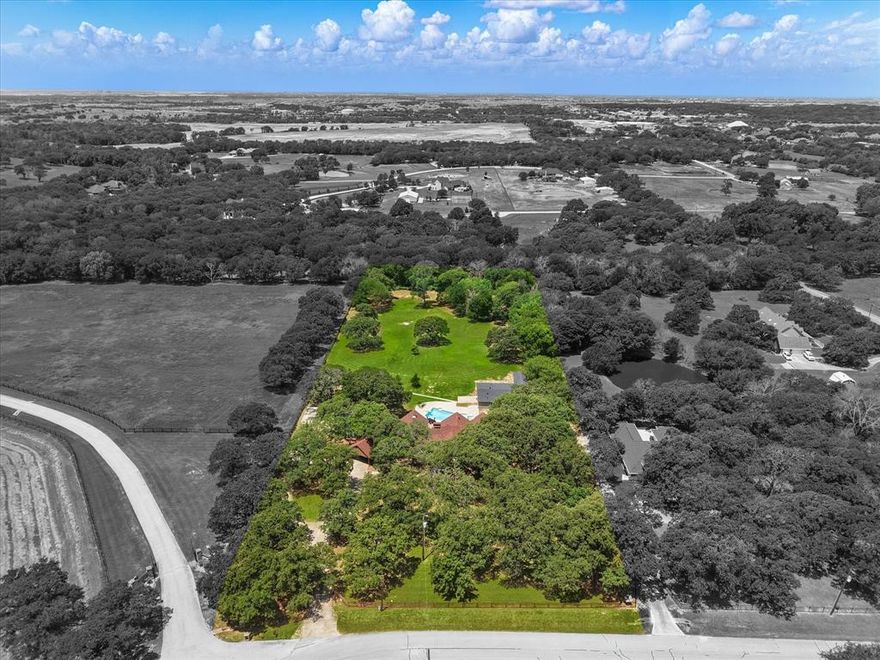 Luxurious Acreage minutes from Top Rated Schools and convenient living! This is the Bartonville lifestyle: refined luxury, effortless comfort, and authentic country charm. This Sprawling Estate resides on 3.57 ACRES offering OVER 7,000 total square feet in ARGYLE ISD and 5 minutes from LIBERTY CHRISTIAN! 
The main house (4,651sqft) showcases five spacious bedrooms including a primary retreat on the first floor featuring a double-sided fireplace that flows into a grand bathroom complete with a private sauna and a large walk-in closet. An expansive living room sets the stage for gatherings large and small, while the screened-in back porch is perfect for for sunny days or chilly evenings under the patio heater. The backyard oasis features a grilling area and diving pool, offering serene views where deer roam or horses ride next door at the horse stables. Recently completed(2025), the 1,848sqft Accessory Bldg is a showstopper with 3 bed, 2.5 bath, and kitchen featuring quartz countertops, Café appliances, and built-in surround sound. This space is ideal for Multi-Generational Living, guests, or a luxurious poolside cabana. A dedicated laundry room with STORM SHELTER adds practicality and peace of mind. Behind the Accessory Building is a tool shed with garage door, ideal for storage or hobby space. The 625sqft Entertainment suite is your private venue—complete with Full Swing golf simulator, premium AV system, custom lighting, and table seating for 12! Watch movies or get the competition started whether it's a family celebration or a corporate retreat, this space leaves a lasting impression! The large carport (easily be an enclosed garage) and the dedicated RV parking pad has Electric and Septic so you are always ready for travel! This is more than a home—it's your own private retreat. One that balances the tranquility of nature with entertainment and fun, all while being minutes from shopping, dining, and entertainment!