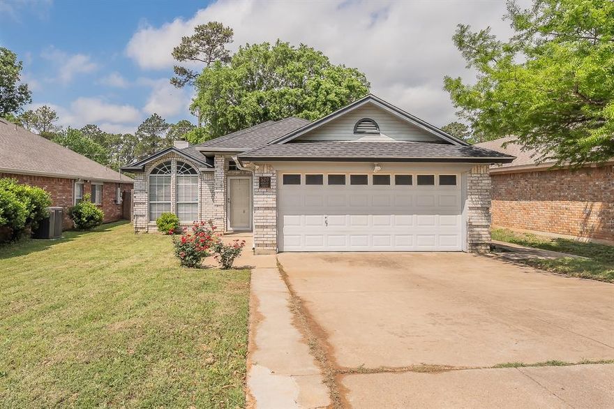 Beautiful one-story, all-brick ranch home nestled in the quiet and convenient Lowery Acres community! This inviting 3-bedroom, 2-bath home offers 1,552 square feet with a functional open-concept layout designed for comfortable everyday living. Step inside to neutral paint tones and hardwood flooring throughout, creating a warm and cohesive feel. The spacious living room features built-in shelving and a cozy wood-burning fireplace, flowing seamlessly into the kitchen complete with stainless steel appliances, a breakfast bar, and a window overlooking the backyard. The split-bedroom floor plan provides added privacy, with a generously sized primary suite offering a garden tub, separate shower, and walk-in closet. Enjoy relaxing or entertaining on the covered back porch overlooking a large, fenced backyard with mature trees. Located within walking distance to a nearby park and just minutes from major highways, shopping, dining, and approximately 30 minutes from DFW Airport—this home offers the perfect blend of comfort, convenience, and charm.