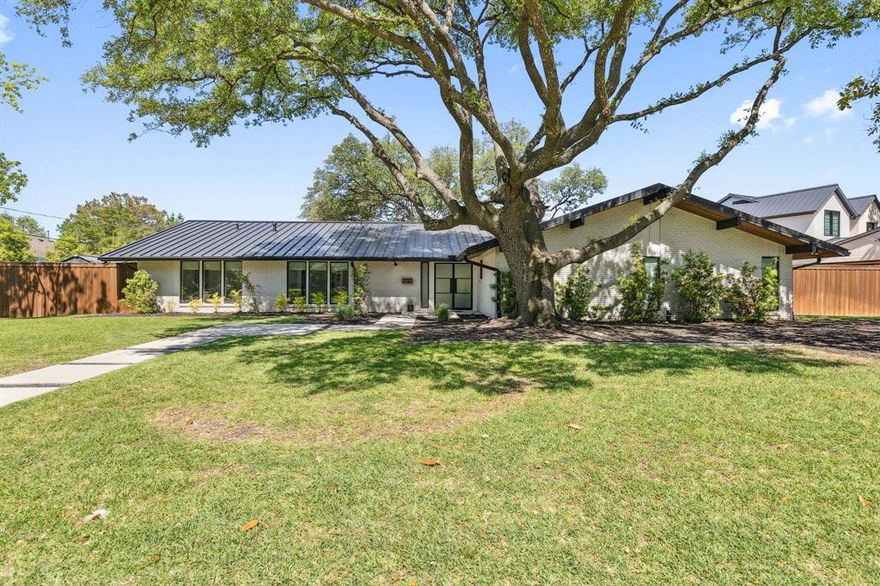 Tucked beneath a canopy of mature trees on a sprawling 178 x 124-ft lot in Preston Hollow’s exclusive Les Jardins, this single-level mid-century modern delivers high-impact design and everyday comfort. Inside, vaulted ceilings with exposed black beams set the tone for the airy, open-concept living space. Anchored by a sleek black brick fireplace with a raised slate hearth, the living room flows into a wall of floor-to-ceiling sliding glass doors, offering views of the resort-style backyard. Wide-plank wood floors add warmth, while natural light floods the space for an inviting yet modern ambiance. The chef’s kitchen is equal parts stylish and functional, with a dramatic waterfall-edge marble island, matte black cabinetry with brass hardware, and premium stainless-steel appliances including a 6-burner gas range and vent hood. A striking wine fridge and built-in microwave wall unit complete the layout. Sleek globe pendant lighting above the island adds a soft modern glow, perfect for hosting or casual meals. The home’s four spacious bedrooms each offer their own ensuite bath, providing comfort and privacy for family or guests. The primary bathroom is a sanctuary—wrapped in large-format tile with a glass-enclosed walk-in shower, deep soaking tub, dual floating vanities, and brushed brass fixtures throughout. Oversized mirrors and modern lighting make the space feel both bright and serene. Outdoors, the home truly shines. The fully turfed yard offers multiple play zones, grilling patios, and a sparkling pool that invites year-round enjoyment. A sport court enhances the lifestyle appeal, while the wide lot and towering trees provide shade and privacy. Every detail has been curated for both dramatic impact and day-to-day functionality. Whether you’re hosting a crowd or enjoying a quiet night in, this home delivers an exceptional experience in one of Dallas’ most sought-after neighborhoods.