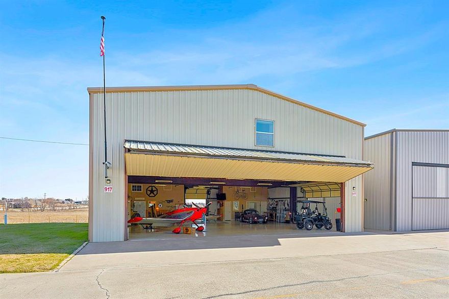Built in 2007, this 5,500 square foot luxury hangar residence is ready for its new owner - being sold turnkey, including most furnishings! The hangar is conveniently located in the northeast portion of the airfield near the north airport entrance gate for quick road access. Just a short taxi to the 3,750' paved and lighted runway! The insulated hangar bay has an old-fashioned walk-in beer and wine cooler, full bath, built-in cabinets, laundry room, epoxy painted floor, ample lighting, two roll-up garage doors for unbelievable ventilation in the summer, and a covered porch out back that runs the width of the hangar. The electric bi-fold hangar door has a 45' wide x 12' tall opening which will accommodate most single engine piston aircraft.  From the hangar, take a walk upstairs and you will quickly forget you are in a metal building! The second floor boasts a luxurious 3-bedroom, 2.5 bath home with open concept kitchen, dining, and living room and high-end finishes and furnishings throughout! Master bath is bigger than most bedrooms! Balcony access through the living area and bedroom with endless views to the east overlooking a 200 plus acres ranch. There is really too much to list! Hangar bay: 50' x 55'; Hangar door opening: 45' wide x 12' tall; 2,750 SF 2nd floor residence; 3-bedroom; 3.5 bath; 4,800 SF land parcel; You own the land (not an airport ground lease); Well water; Community septic; 100LL fuel available on the airfield. Hicks Airfield is just minutes from fine dining, brand new Kroger and Lowes, and only 15 minutes to the internationally famous Fort Worth Stockyards! This hangar will make a great primary residence, second home, man cave, or woman cave!