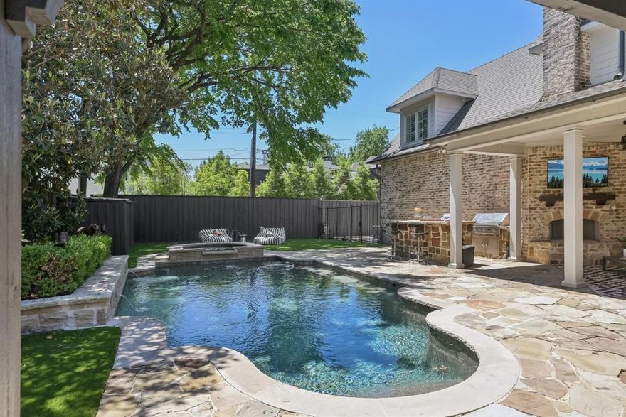 Discover refined living in this exceptional stone Colonial crafted by renowned builder Ellen Grasso & Sons. Ideally located and zoned to highly acclaimed HPISD, including sought-after Boone Elem. Set on an expansive 70’ x 160’ lot, this beautifully updated home offers an open-concept floor plan designed for sophisticated entertaining and effortless everyday living. A grand entry welcomes you, flanked by an elegant formal living room w fireplace and a generously proportioned dining room. The dining space flows seamlessly into a fully-appointed wet bar featuring a wine cooler, ice maker, and reverse osmosis system—perfect for hosting with style. The gourmet kitchen is a statement in luxury showcasing Calacatta Danby marble countertops, an oversized island, 2 ovens, a 6-burner gas cooktop w griddle, appliance garage, and a sunlit breakfast room. The adjoining family room is warm and inviting, centered around a fireplace and overlooking the serene backyard retreat. The first floor also offers a private secondary bdrm with ensuite bath, an office with custom built-ins and a private entrance, and a beautifully appointed powder bath. Upstairs, the primary suite is a true sanctuary, complete with a sitting area, dual vanities, a jetted soaking tub, separate shower, and a spacious walk-in closet. Four additional ensuite bdrms, each with walk-in closets, provide exceptional comfort and privacy. A generous game room and full-size laundry room w built-in cabinetry and a sink complete the upper level. Step outside to your backyard oasis featuring a sparkling pool and spa, fireplace, covered seating area, pergola, built-in grill, beverage refrigerator, and turfed lawn—an entertainer’s dream and a tranquil escape. Addl enhancements: whole-home water purification system, generator, and integrated smart home tech w app-controlled systems and appliances. An extraordinary opportunity to own a timeless residence in one of Dallas’ most coveted neighborhoods.