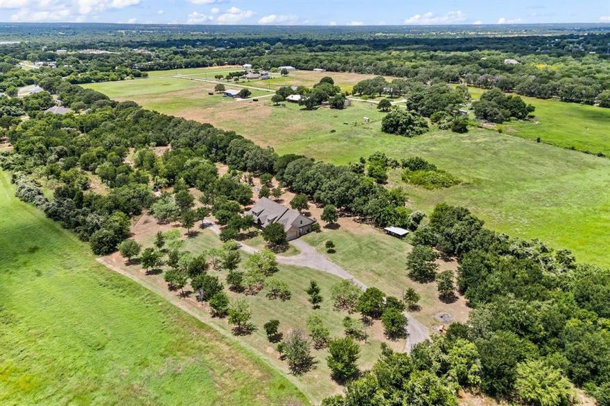 SEARCH YOUTUBE FOR VIDEO OF THIS HOME! USDA Financing Avail! Escape to your own private, tree-filled retreat on more than 2ac in Northwest ISD! NO HOA! Spray Foam Insulation! Radiant Barrier! Move in immediately or pour a little TLC into the home to make it yours! Room on the land to build more structures like a 2nd home, a pickleball court, etc! Unique property w-beautiful mature trees, offering both shade & scenery! The spacious WRAPAROUND covered porch & oversized covered back patio create the perfect setting for sipping coffee, entertaining guests, or simply soaking in the peaceful surroundings! Inside, tall ceilings & a split-bedroom layout give the home an open yet functional feel w-all 4 bedrooms being on the primary level! Not to miss is your ENORMOUS chef-like kitchen w-GRANITE countertops, a HUGE island, an EXPANSIVE breakfast bar area great for entertaining, custom cabinetry w-multiple hidden pullouts, a stainless-steel appliance package, a butler's pantry area, a 5-burner double oven range... all packaged in a design that opens to the family room! The owner’s suite is tucked away from the other bedrooms for added privacy & quietness away from a busy household! It boasts a spa-like en suite & a HUGE owner's closet! The 3 secondary bedrooms all are spacious in size, have ceiling fans, 2-inch blinds & nice sized closets! The upstairs game room is ENORMOUS & provides GREAT flexibility that could easily serve as a 5th bedroom (if needed) as there is a closet & half bath upstairs as well! Also upstairs is your very own MEDIA ROOM! The garage is EXTRA deep (24') easy for truck parking! Enjoy FREE WATER with your own water well filtration system! There's even a chicken coop ready for your backyard hobby farm! And you are just 2 miles from Eagle Mountain Lake & only 4.5 miles to Hwy 287 w-quick access to a Super Walmart, Starbucks, auto shops, a UPS Store, a BRAND-NEW Texas Roadhouse & so much more! This property truly blends rural charm w-everyday convenience!