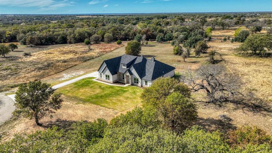 Welcome to this stunning 2,884 sq ft residence in highly sought-after Peaster ISD, offering luxury living in a serene country setting. Step inside to soaring ceilings and a dramatic floor-to-ceiling brick fireplace with a floating mantle, creating a warm and inviting focal point in the main living area. Massive windows frame the gorgeous 2.454-acre treed lot, bringing natural light and picturesque views into every corner. The thoughtfully designed layout features 4 bedrooms plus a dedicated office that can easily flex as a 5th bedroom, den, or private retreat. A spacious additional bonus room provides even more versatility for entertainment, play, or media. Hand-scraped hardwood floors flow throughout the main spaces, complementing a chef-inspired kitchen appointed with floor-to-ceiling shaker cabinetry, a large quartz island, and a generous corner pantry. The oversized primary suite is a private sanctuary with tray ceiling, and an expansive ensuite bath complete with dual vanities, a walk-in shower, separate soaking tub, and seamless access into a massive walk-in closet. From there, enjoy a beautifully designed pass-through into the galley-style laundry room and directly into the mudroom—an elevated and functional flow that enhances everyday living. Enjoy wood-burning fireplaces both inside and out, including on the large back patio overlooking the lush, partially fenced property with a fully fenced section ideal for pets or play. Located in a quiet cul-de-sac and just 10 miles north of downtown Weatherford, this remarkable home offers the perfect blend of luxury, privacy, and modern convenience.