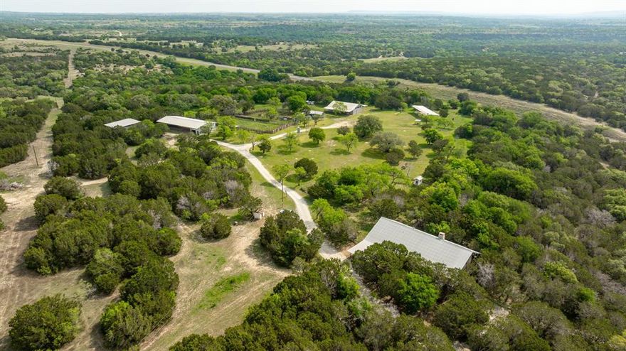 This 506± acre property in Hamilton County offers an opportunity for investment, recreation, or residential use in the heart of Hamilton, Texas. This property has been in the family as a working bison ranch, adding to its unique character and legacy. Conveniently located just 13 miles from both Hico & Hamilton, two charming towns with excellent restaurants, grocery stores, and medical services, this property is easily accessible with U.S. Highway 281 bisecting the land. Approx.  400± acres lie on the west side of the highway, while 106± acres sit on the east. Both tracts have Highway 281 frontage & CR frontage on the south boundary side.

The main entrance, marked by custom stone gates, leads to a distinctive stucco lodge nestled on the western tract. This spacious lodge was built for entertaining, with a massive great room, open-concept kitchen and dining area, vaulted ceilings, and a loft with a full bath. There is a primary bedroom with a separate entrance and a kitchenette, as well as another guest room and a laundry room. Downstairs includes a large kitchen & suite, a full bath, and a half bath. See the floor plan for details on the flexible layout, perfect for hosting large groups or family gatherings.

Just outside the lodge are several key improvements, including a large metal workshop, cattle pens, barns, and an original windmill, ideal for a working ranch or recreational hunting retreat. The landscape is a scenic mix of native hardwoods, such as oak and juniper, with gently rolling terrain and one stock tank that supports livestock and wildlife.

On the West tract, a separate entrance off CR 105 provides access to a peaceful area featuring large oak trees, a water well, an RV hookup, and electricity, making it an ideal future homesite or weekend getaway. With its versatile layout, extensive road frontage, and existing infrastructure, this property is well-suited for a hunting lodge, family compound, or long-term investment.