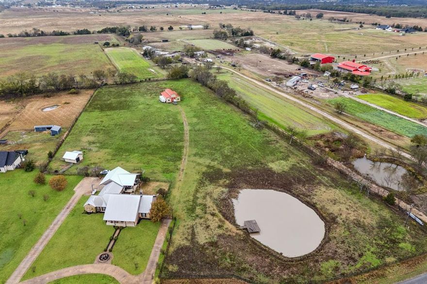 Just outside the hustle and bustle of Dallas, you’ll find your own piece of Texas. Nearly 7 acres of rolling pastures, open skies, and quiet so deep you can hear the wind whispering through the grass. This custom home is built for country living, with space to roam, room for your passions, and every detail designed for comfort. Inside, warm hardwood floors lead through the open, flowing living and kitchen areas, seamlessly connected and perfect for gatherings with a walk-in pantry and two doors opening directly to your backyard oasis. A dedicated home office, a utility room with its own entrance and sink, and flexible rooms—including a 4th bedroom for guests, crafts, or media—round out the thoughtful layout, while the primary retreat offers a cozy fireplace and peaceful sanctuary after a full day outdoors. Outside, the lifestyle truly comes alive. Your backyard is a private retreat, fully fenced for peace of mind. The 3-stall horse barn—with its own bathroom, separate electric, and septic—is ready for your horses or a potential income opportunity. Step onto the covered patio and full outdoor kitchen, where pastures stretch to the horizon, a serene pond mirrors the sky, and fields glow in golden sunset light—perfect for entertaining or relaxing. An oversized 3-car garage, chicken coop, storage shed, RV hookup, and multiple gated entrances make country living effortless and versatile. AG-eligible and HOA-free, this is a place to live life your way—close enough to Dallas for convenience, yet far enough to enjoy quiet country charm with nearby schools and easy highway access. Wide-open skies. Rolling pastures. Quiet beauty. Freedom. This is Texas living, exactly as you imagined it.