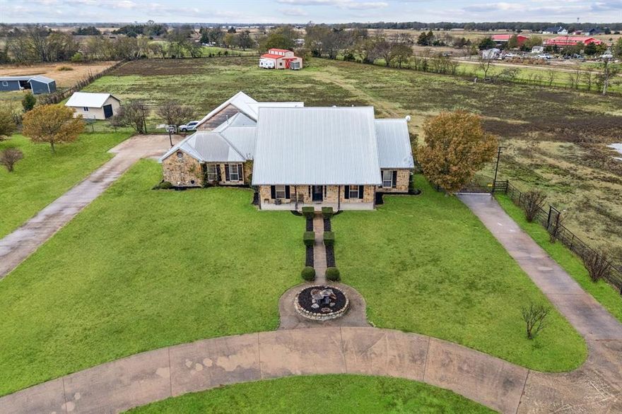 Just outside the hustle and bustle of Dallas, you’ll find your own piece of Texas. Nearly 7 acres of rolling pastures, open skies, and quiet so deep you can hear the wind whispering through the grass. This custom home is built for country living, with space to roam, room for your passions, and every detail designed for comfort. Inside, warm hardwood floors lead through the open, flowing living and kitchen areas, seamlessly connected and perfect for gatherings with a walk-in pantry and two doors opening directly to your backyard oasis. A dedicated home office, a utility room with its own entrance and sink, and flexible rooms—including a 4th bedroom for guests, crafts, or media—round out the thoughtful layout, while the primary retreat offers a cozy fireplace and peaceful sanctuary after a full day outdoors. Outside, the lifestyle truly comes alive. Your backyard is a private retreat, fully fenced for peace of mind. The 3-stall horse barn—with its own bathroom, separate electric, and septic—is ready for your horses or a potential income opportunity. Step onto the covered patio and full outdoor kitchen, where pastures stretch to the horizon, a serene pond mirrors the sky, and fields glow in golden sunset light—perfect for entertaining or relaxing. An oversized 3-car garage, chicken coop, storage shed, RV hookup, and multiple gated entrances make country living effortless and versatile. AG-eligible and HOA-free, this is a place to live life your way—close enough to Dallas for convenience, yet far enough to enjoy quiet country charm with nearby schools and easy highway access. Wide-open skies. Rolling pastures. Quiet beauty. Freedom. This is Texas living, exactly as you imagined it.