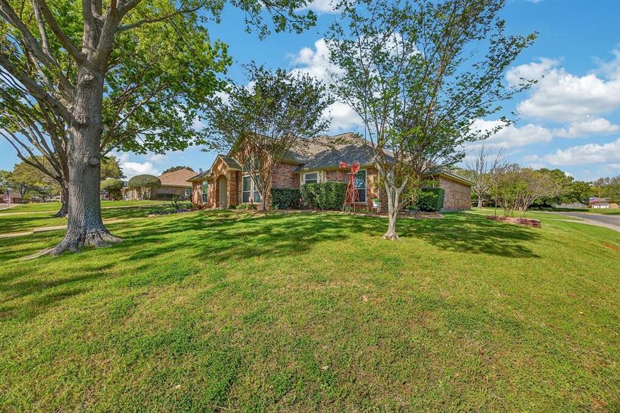 Nestled on a quarter-acre corner lot shaded by mature trees, this custom one-story home offers an unbeatable location for families and outdoor enthusiasts alike. Just minutes from the premier fishing and boating destination of Lake Lewisville, you can enjoy weekend adventures on the water with ease. Even closer to home, a quick two-block walk leads you to Doubletree Ranch Park, where you will find scenic walking trails, a peaceful fishing pond, a community concert venue, and a fun splash pad where kids can cool off during the warm Texas summers.
Inside, the home features three spacious living areas designed to give everyone room to relax and gather. The huge family room serves as the heart of the home, highlighted by a stunning floor-to-ceiling brick fireplace that creates a warm and inviting atmosphere. A separate game room or media room with a convenient wet bar provides the perfect space for entertaining friends or hosting family movie night. In addition, the enclosed covered patio offers year-round comfort under the homes updated central heating and air conditioning, creating a versatile bonus space that is not included in the home’s stated square footage.
The island kitchen is both functional and welcoming, boasting durable granite countertops, black appliances, and beautiful solid red oak cabinets that provide ample storage. The formal dining has a massive vaulted ceiling and can easily be converted to an office. The thoughtfully designed layout includes split secondary bedrooms that offer privacy from the primary suite. The spacious primary suite includes its own ensuite bath, creating a comfortable retreat at the end of the day.
This cozy home is ideal for a growing family, thanks to its 3 flexible living spaces and prime location near parks, recreation, and everyday conveniences. Spend evenings hosting backyard barbecues on the large, covered patio or take a short stroll to enjoy the many amenities at the nearby Doubletree Ranch Park.