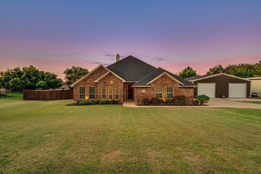 Welcome to 409 Emerald Court! Meticulously maintained inside and out, this custom-built 4-bedroom home sits on just under an acre right outside city limits and offers a rare combination of comfort, functionality, and lifestyle. From the moment you arrive, the pride of ownership is evident. The heart of the home is a comfortable, open living space that connects effortlessly to the kitchen and dining area. The kitchen offers granite countertops, custom cabinetry, a walk-in pantry, and an island designed for both everyday use and entertaining. The primary bedroom provides a private retreat with an en-suite bath, soaking tub, walk-in shower, and large walk-in closet. Step outside to your own backyard escape, complete with a saltwater pool, covered patio, and misting system, ideal for entertaining or unwinding under the Texas sky. The property features a chicken coop, raised garden beds, and fruit trees adding both charm and functionality. The 2,000 sqft insulated shop is a true standout, featuring a heated and cooled office and bathroom, plus a separate dedicated paint booth room. The opportunities are endless with this impressive 40x50 space. An expanded driveway offers ample parking, and a storm shelter inside the garage provides peace of mind. Surrounded by mature trees and beautiful landscaping, this property offers country living just minutes from town. With no HOA and no city taxes, yet convenient access to shopping, dining, schools, and major highways, you’ll enjoy the perfect balance of privacy and accessibility.