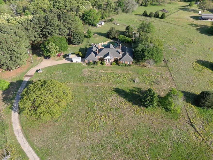 Custom Brick Estate located 2 miles from city limits and hospitals, 16 acres, not HOA.  Discover the perfect blend of comfort and sophistication in this custom 4 bedroom 3 bath brick home, nestled on nearly 16 scenic acres of rolling hills along FM 753. Boasting double primary suites, this spacious residence is ideal for multigenerational living or accommodating guests in luxury.  Enjoy a chef’s dream kitchen, expansive living room, cozy den, and a gas fireplace that anchors the home with warmth and charm. Step outside to your private gunite pool, perfect for relaxing or entertaining under the East Texas sky.  With ample room to roam, this home offers endless opportunities to add your personal touch and make it truly yours. Whether you're looking for peaceful country living or a stunning place to host family and friends, this property delivers.  Don't miss out on this rare opportunity so close to town yet surrounded by nature. Only two miles out of the city limits no city taxes or POA fees.