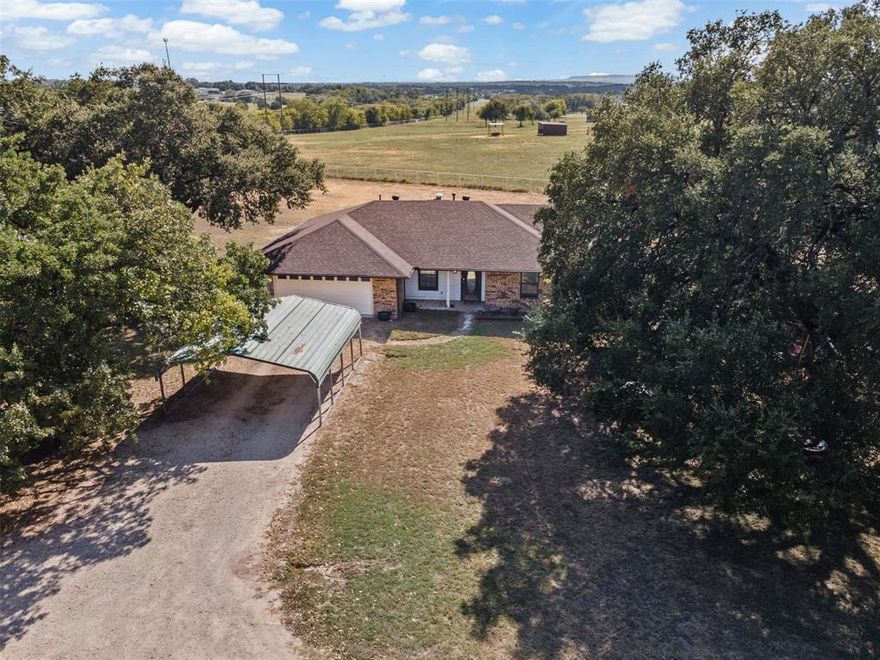 This property qualifies for USDA!Sunsets, space, and serenity set on 4 peaceful acres in Granbury, this property offers the perfect blend of quiet country living and practical amenities. The spacious 4 bedroom, 2 bath home features an open layout filled with natural light and hilltop views that stretch for miles. A cozy fireplace anchors the main living area, creating a warm and inviting space for relaxing evenings or family gatherings.  Outdoors, you'll find a large detached shop for projects, storage, or business use, plus a dedicated RV cover with electric and its own septic hookup, ideal for guests, full-timers, or travel enthusiasts. With no HOA, you’ll have the freedom to create the lifestyle you want, whether that’s gardens, animals, or future expansions.  And when it comes to evenings, this property truly shines, enjoy spectacular Texas sunsets year round, and on July 4th and New Year’s, watch the sky light up with fireworks from your own backyard, thanks to panoramic views of nearby celebrations.  All this just minutes from Lake Granbury, historic downtown, local dining, and top-rated Granbury ISD schools — with quick access to Hwy 377 for an easy commute.